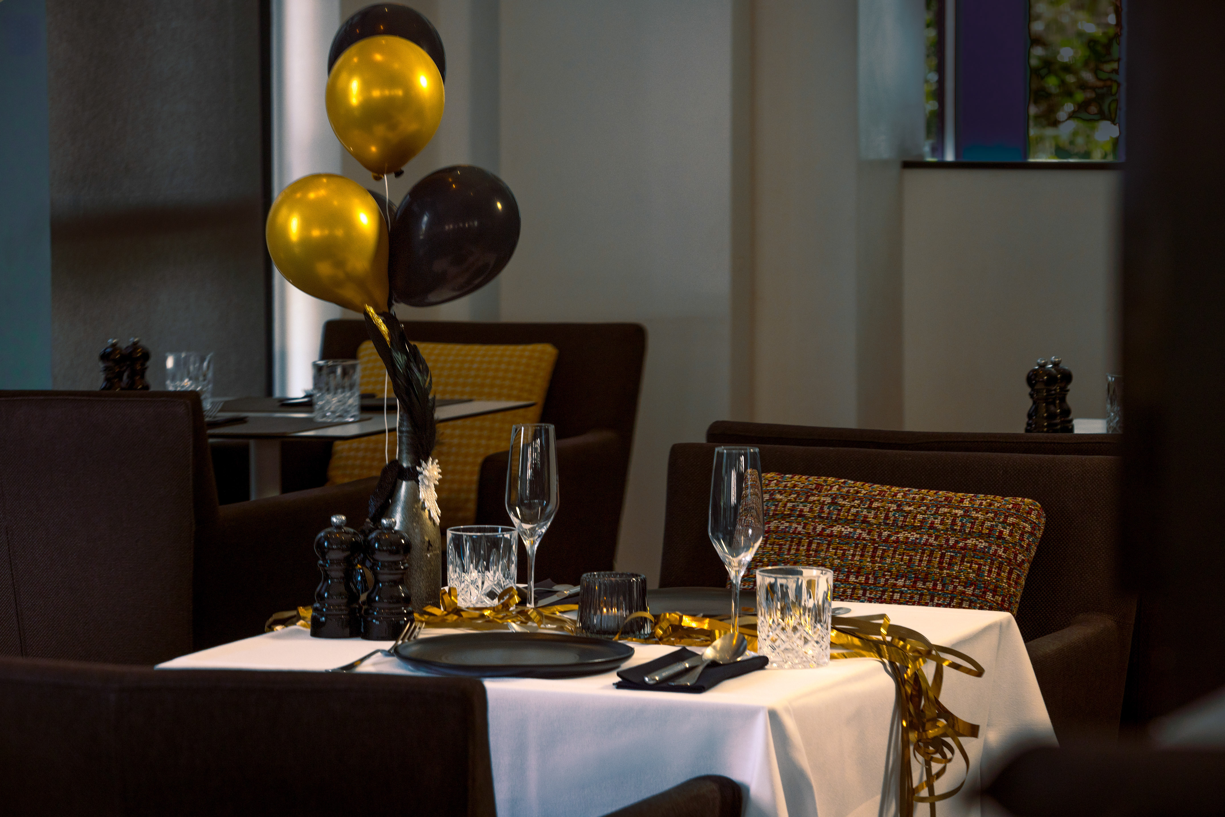 Festive restaurant table with gold and black balloons, elegant place settings.