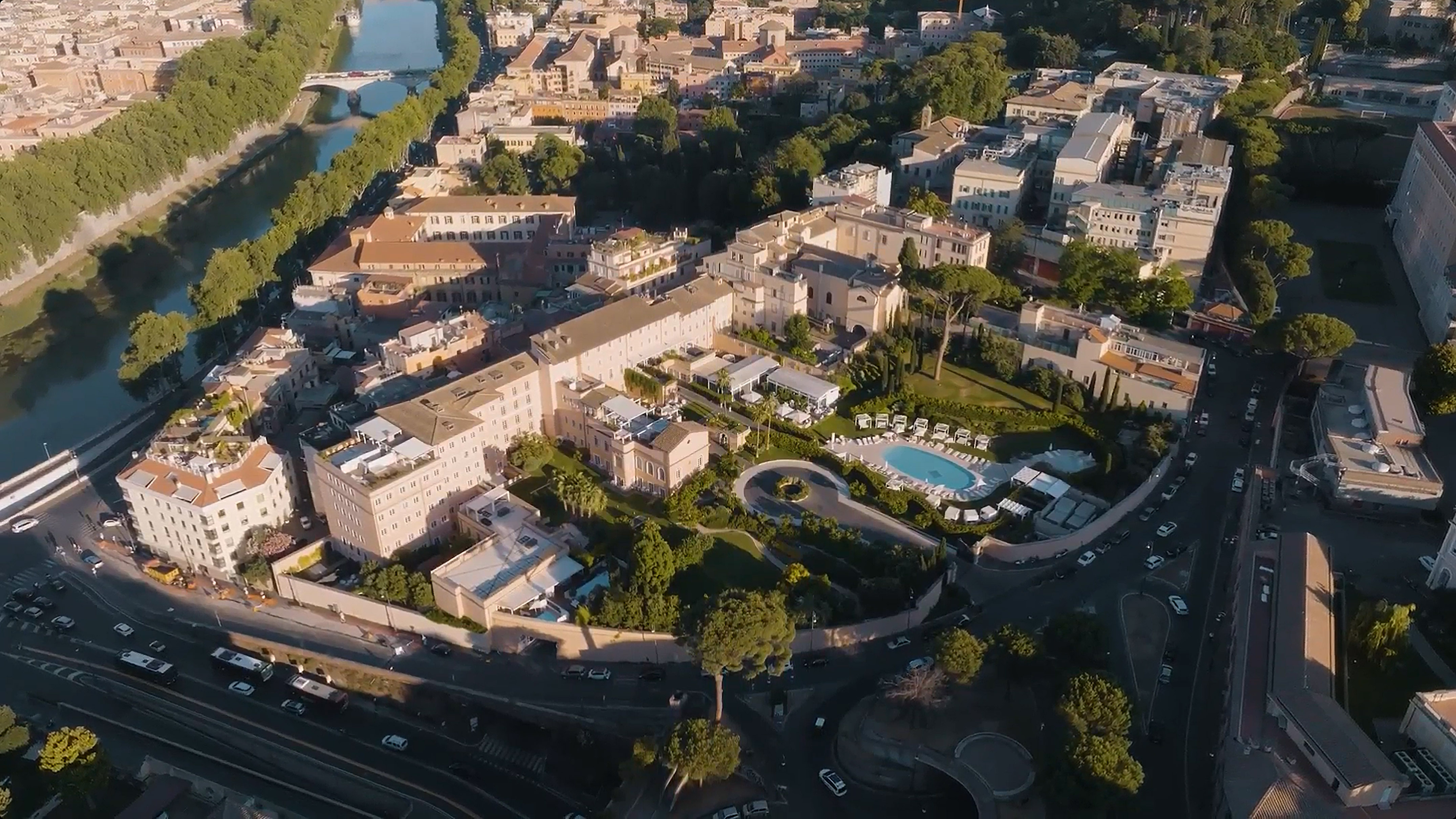 Aerial Rome view: elegant hotel, pool, and gardens beside the Tiber River.