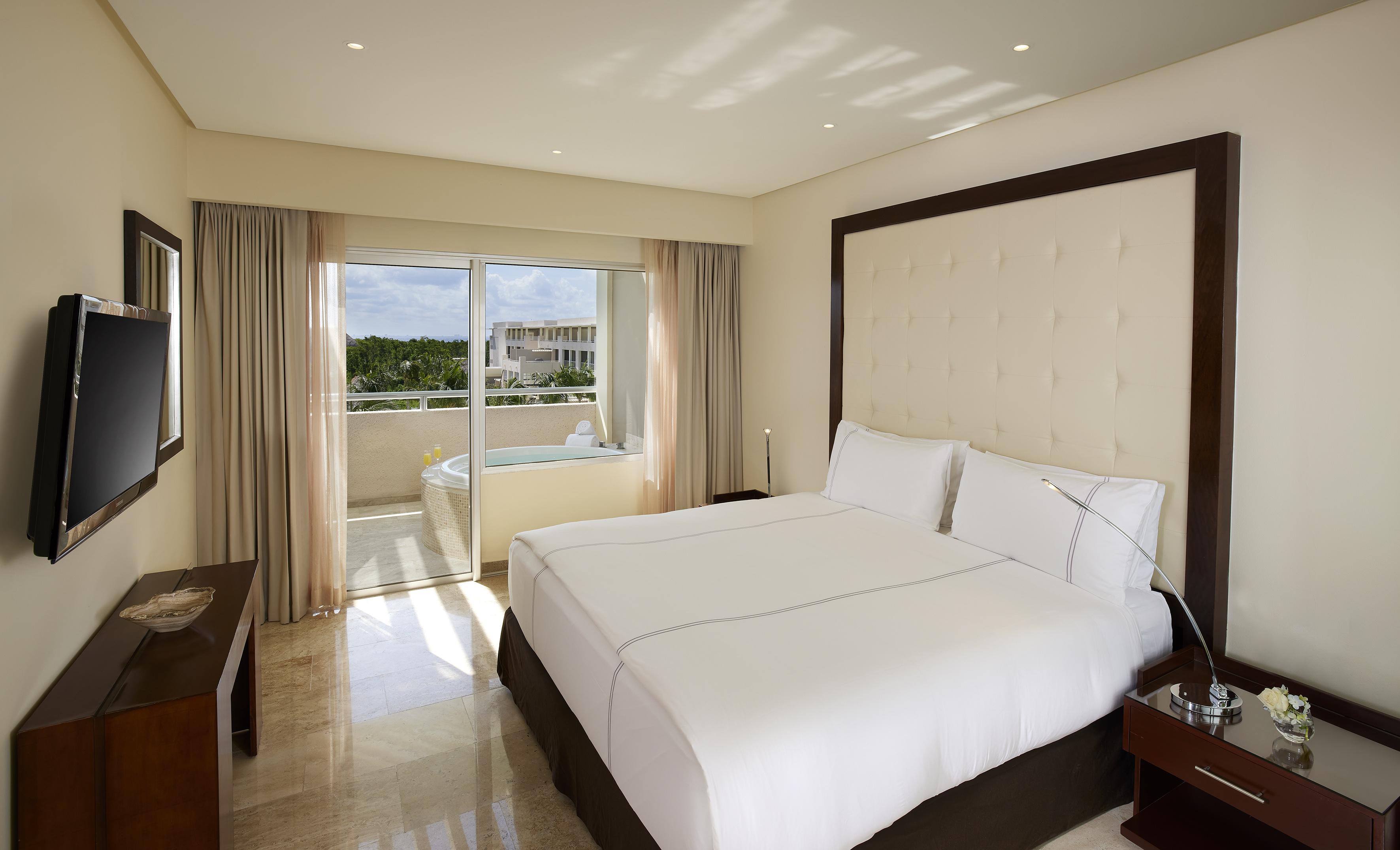 Luxurious hotel bedroom with king bed, private balcony, and outdoor jacuzzi.