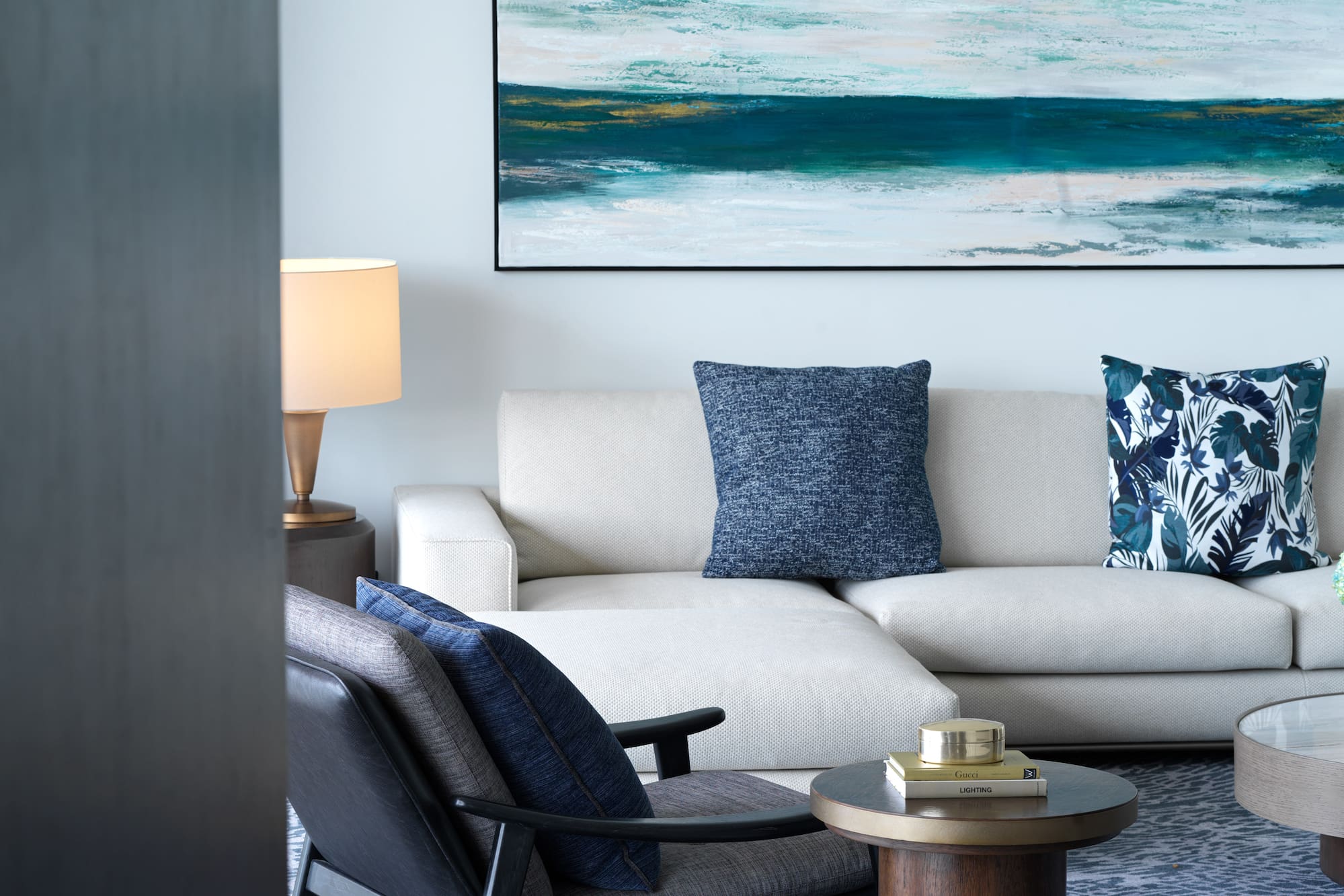a white couch with blue pillows and a painting on the wall