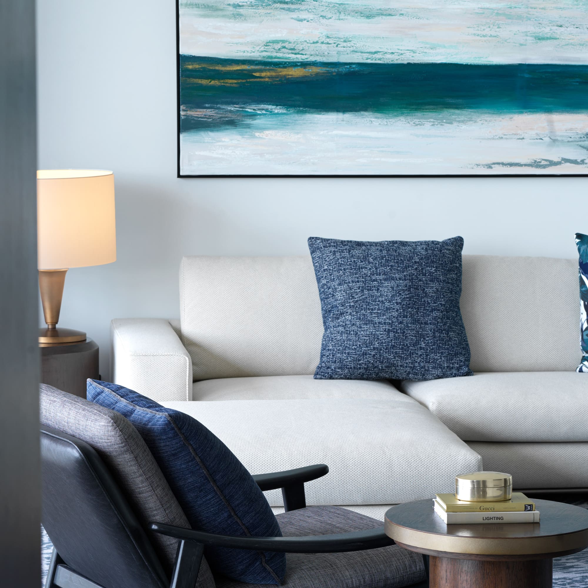 a white couch with blue pillows and a painting on the wall