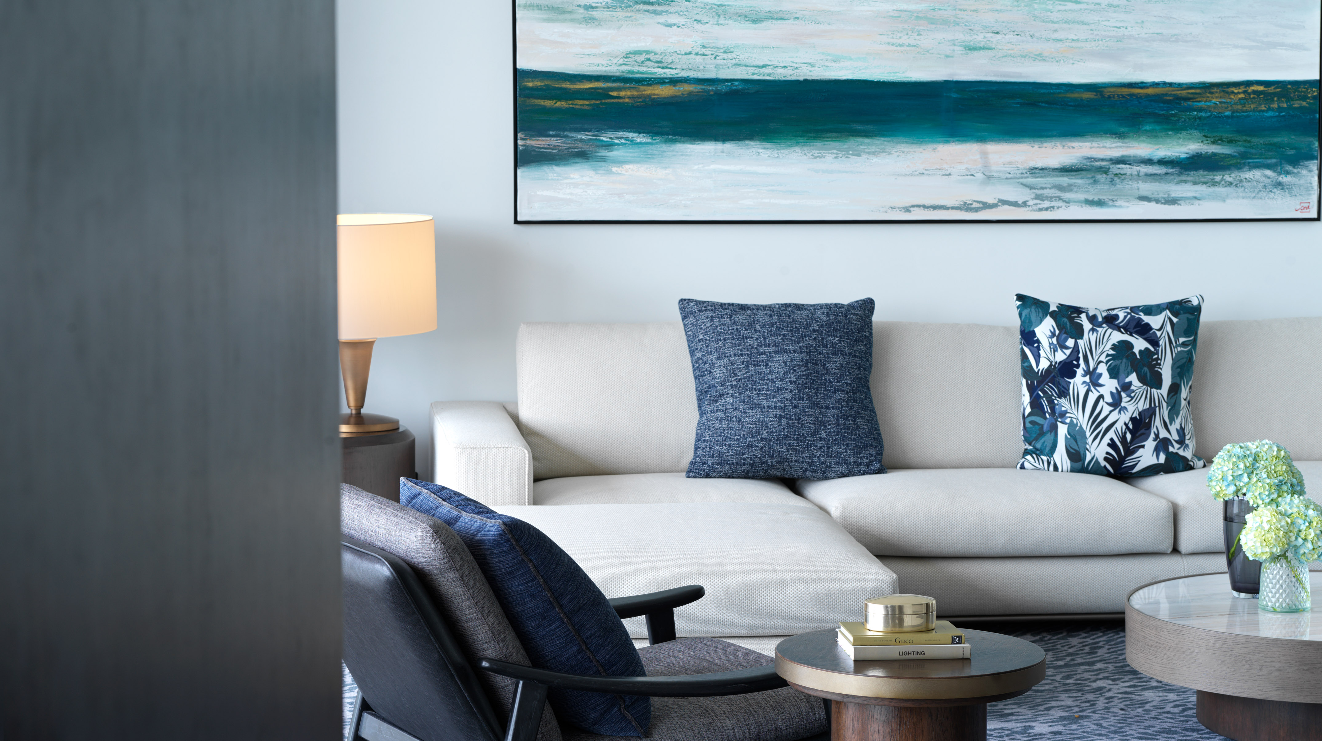 Modern living room interior with cream sofa, blue cushions, and abstract art.