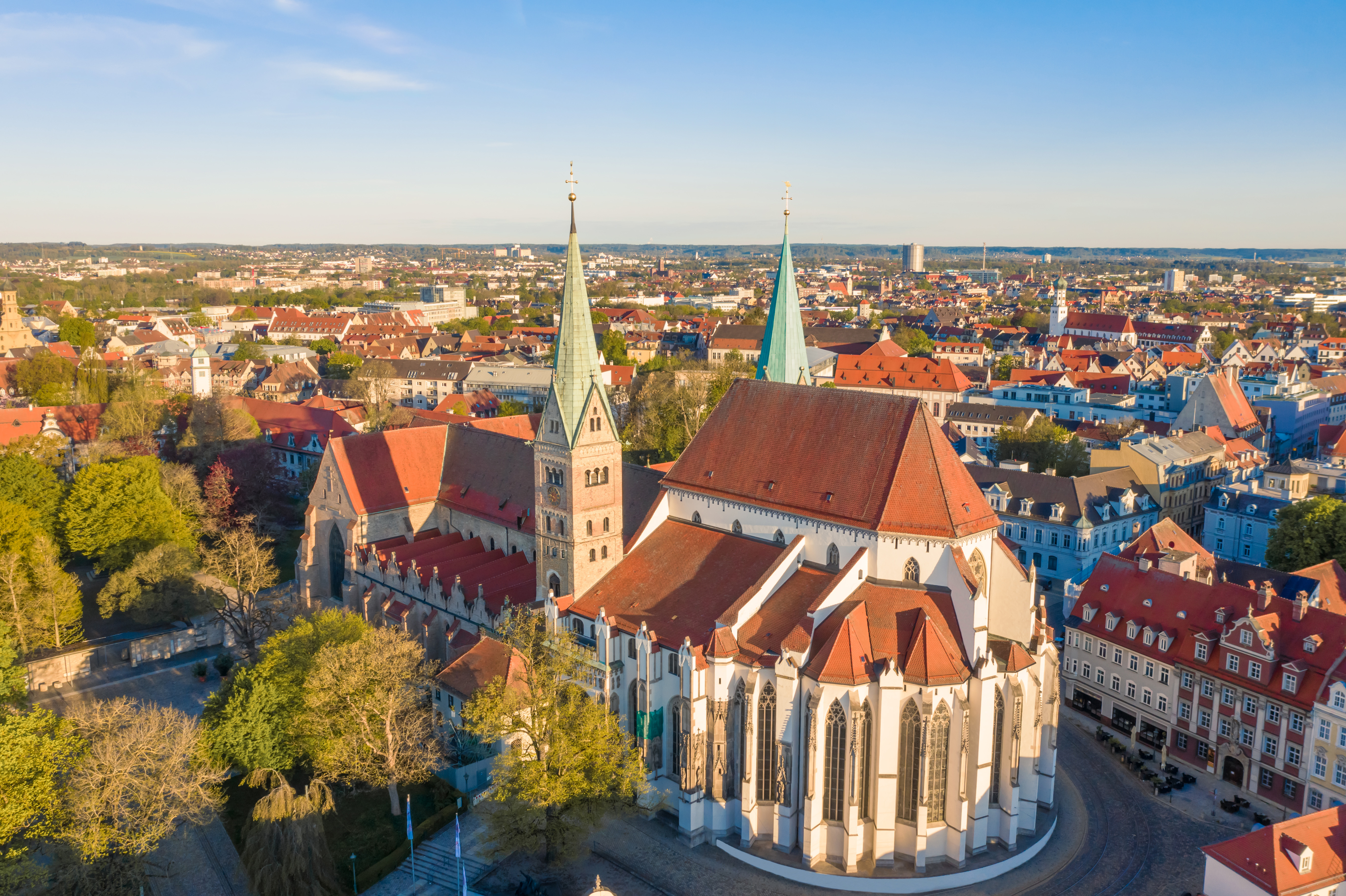 Aerial view of Paderborn Cathedral and historic city with red roofs under blue sky.