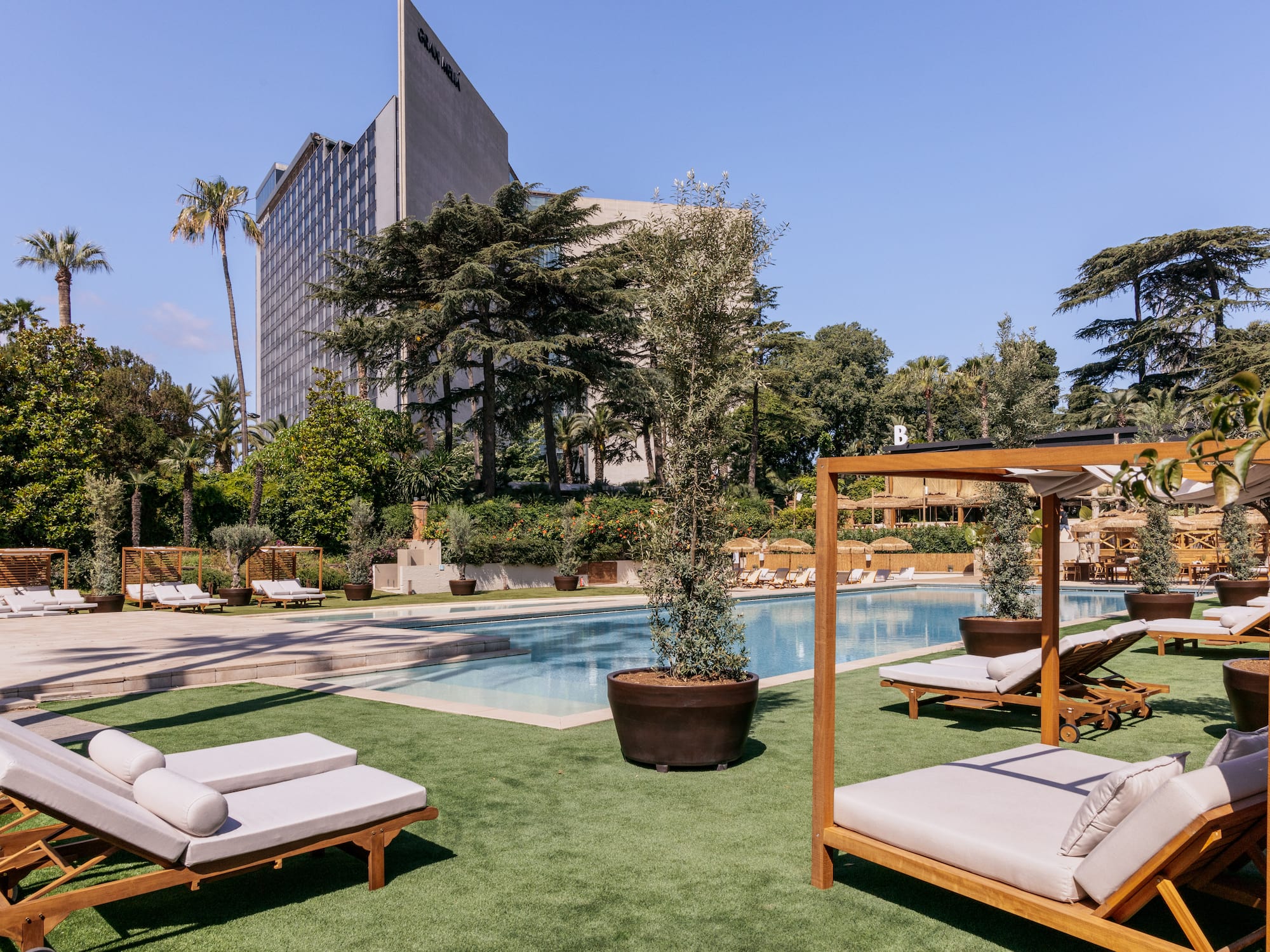 a pool with lounge chairs and trees in the background
