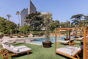 a pool with lounge chairs and trees in the background