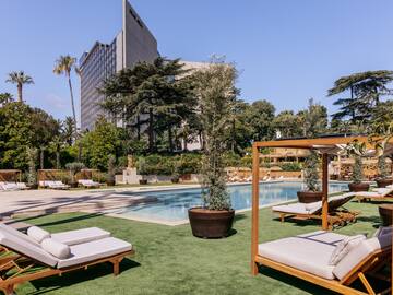 a pool with lounge chairs and trees in the background