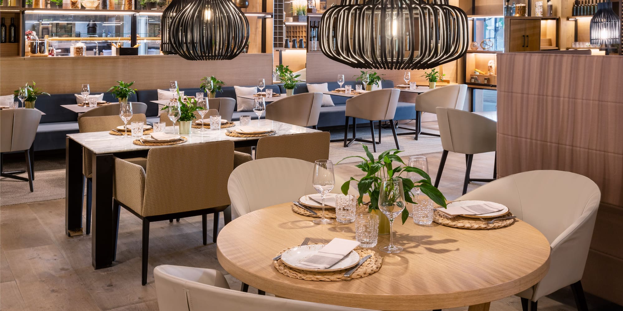 Modern restaurant dining room with set tables and stylish black pendant lights.