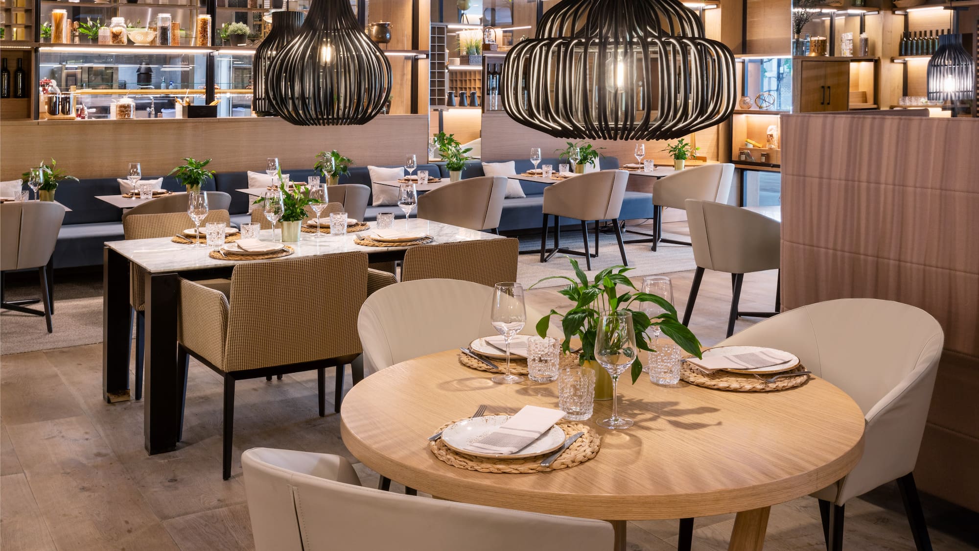 Modern restaurant dining room with set tables and stylish black pendant lights.