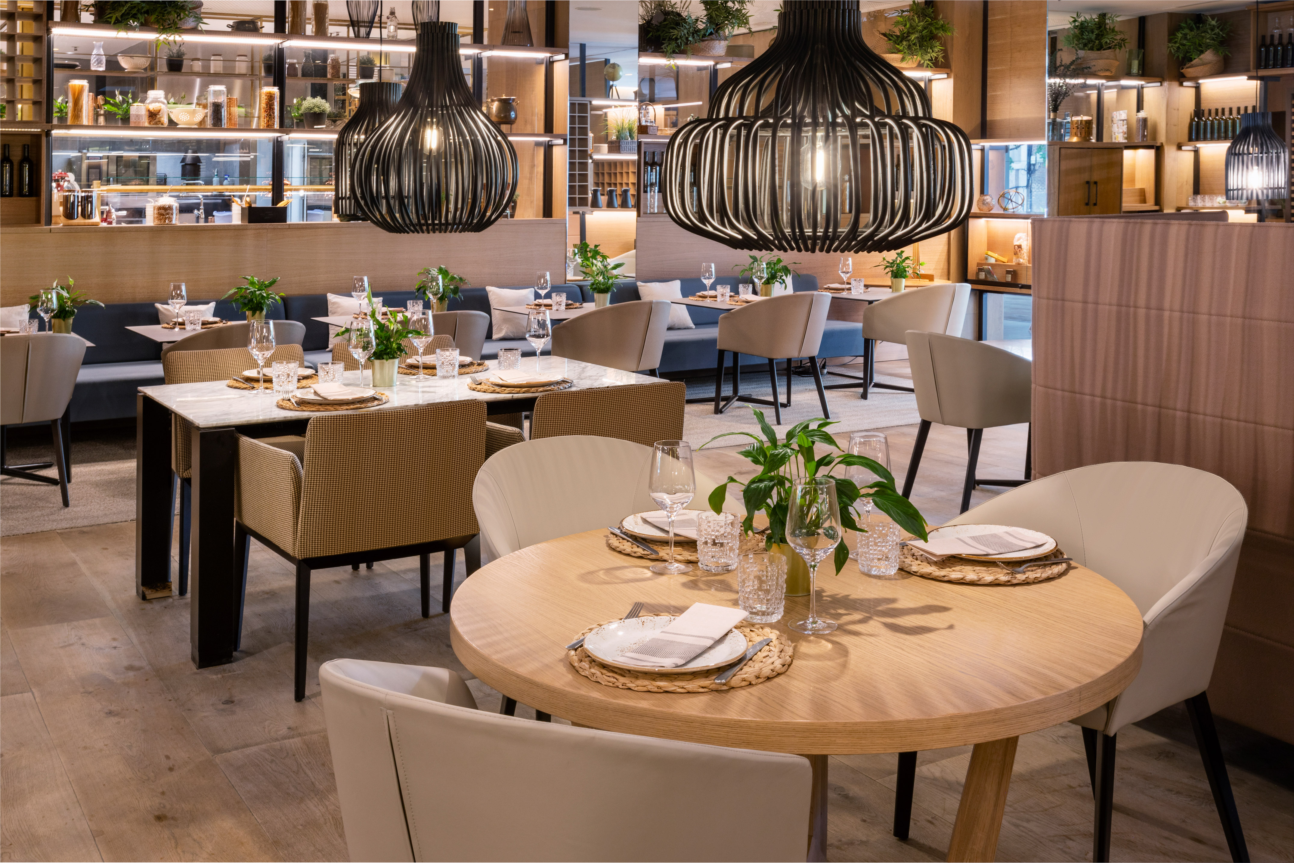 Modern restaurant dining room with set tables and stylish black pendant lights.