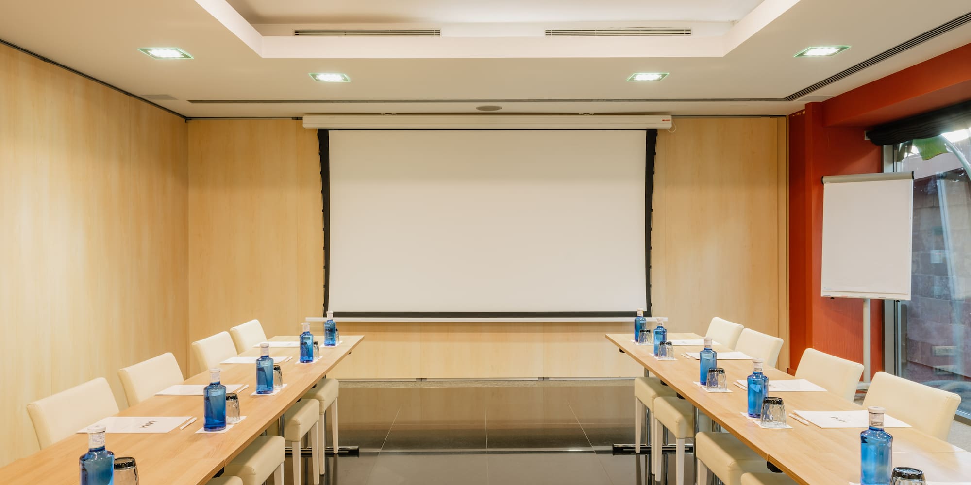 a room with a projection screen and tables and chairs