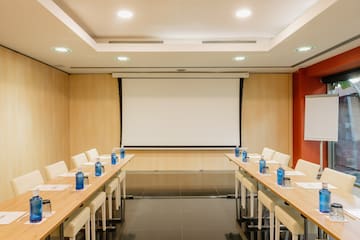 a room with a projection screen and tables and chairs