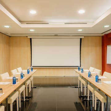 a room with a projection screen and tables and chairs