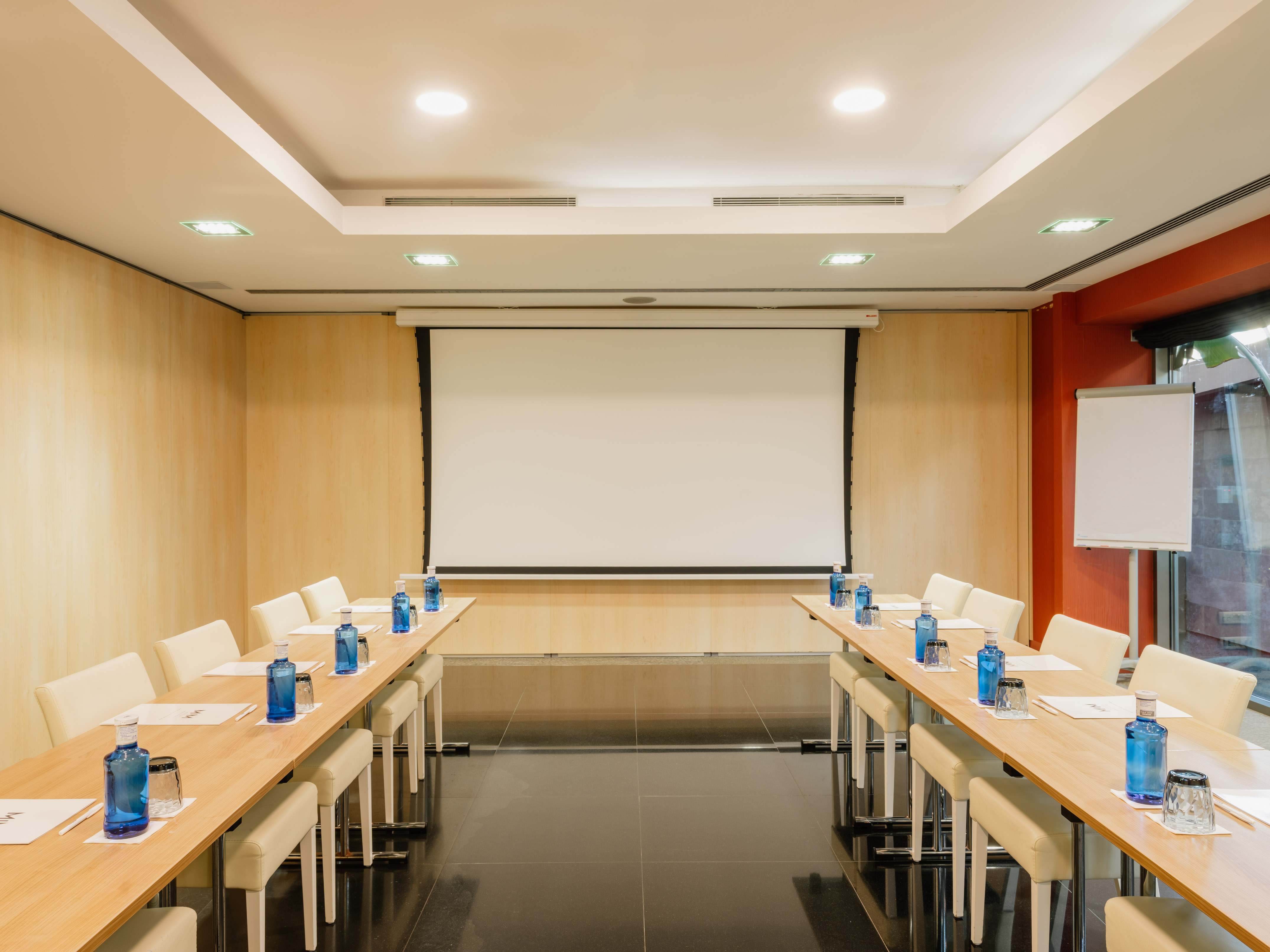 a room with a projection screen and tables and chairs.