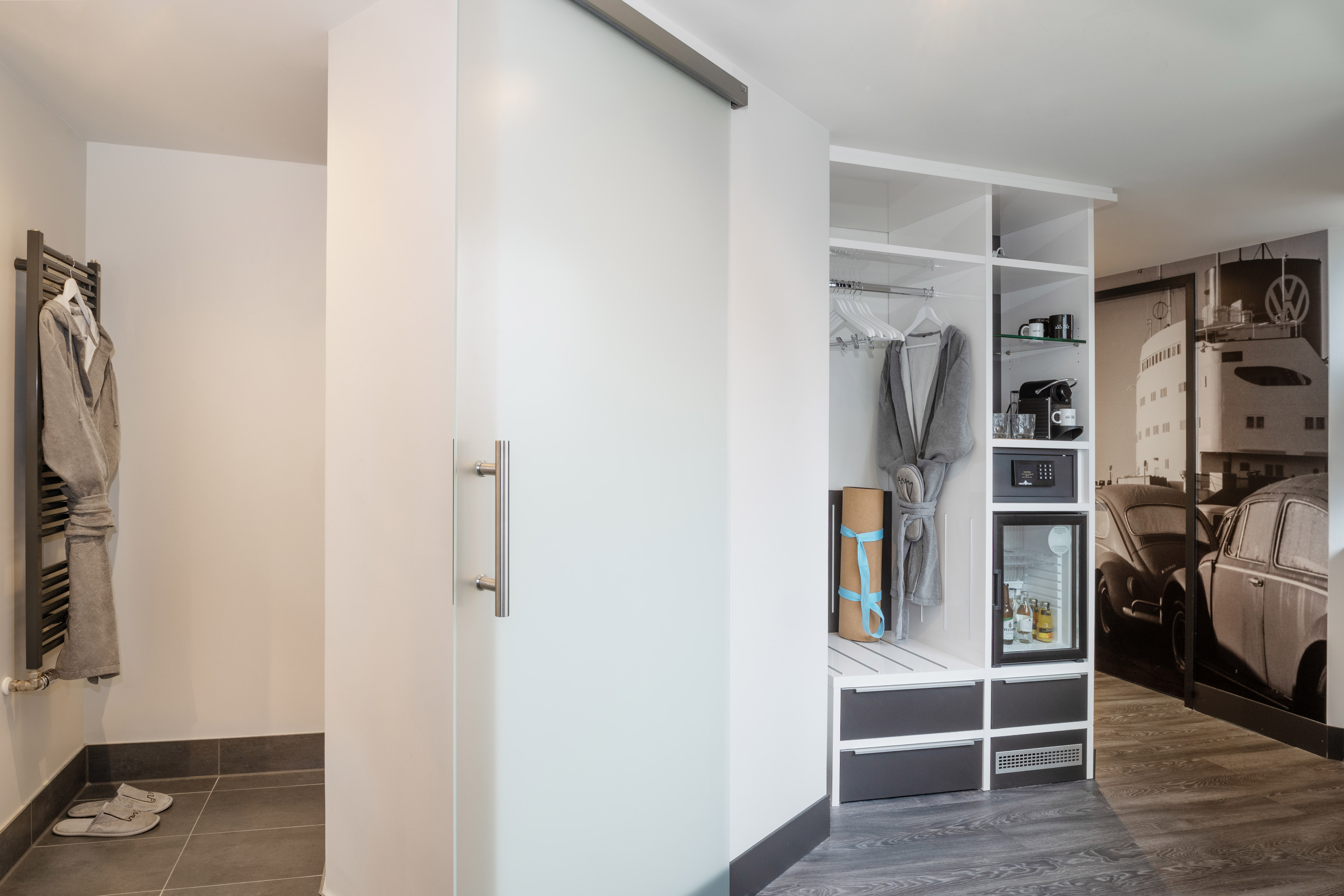 Modern hotel wardrobe with frosted sliding door, mini-bar, coffee, and safe.
