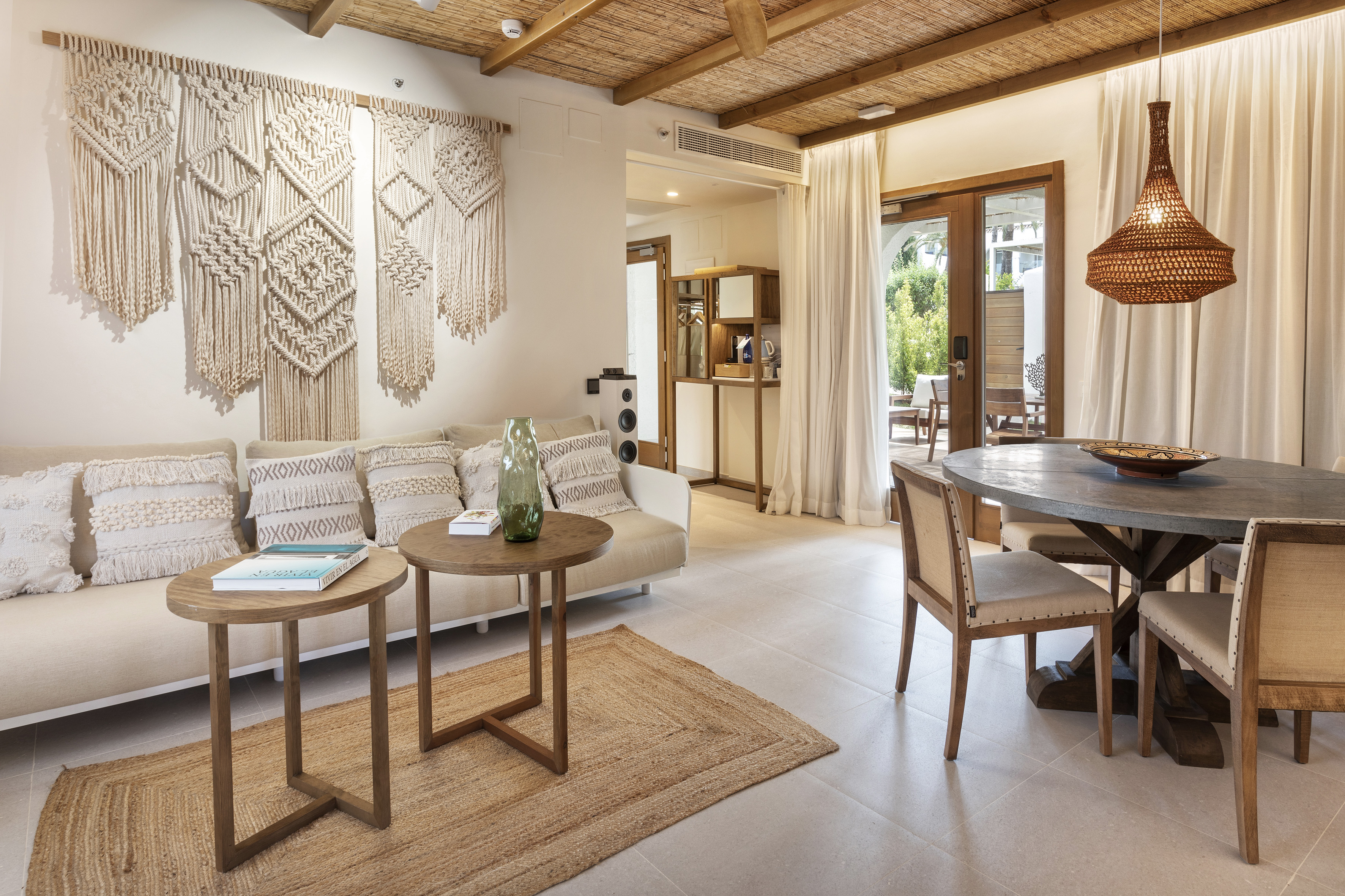 Bohemian living and dining area with macrame, jute rug, rattan pendant.