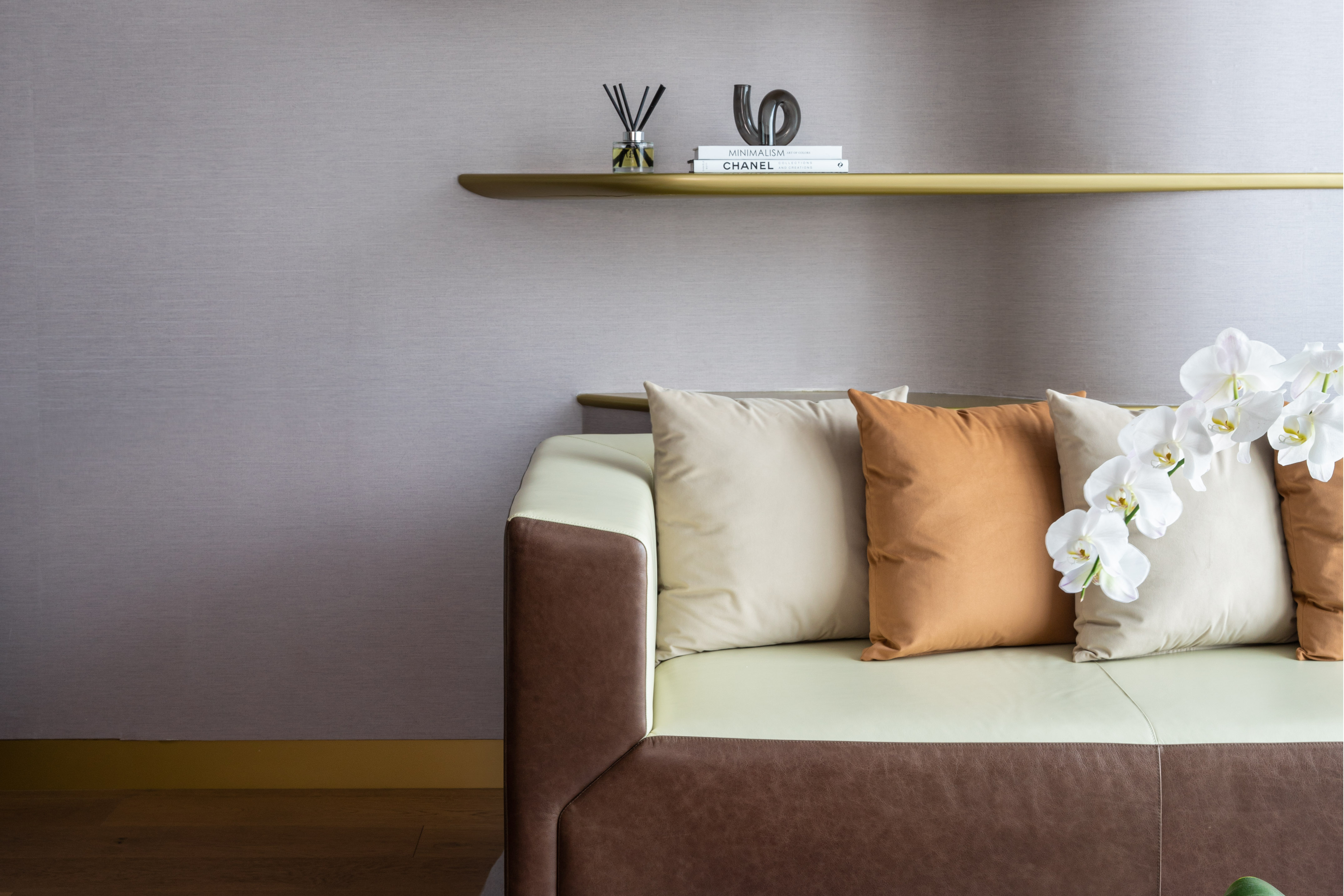 Elegant two-tone sofa, throw pillows, white orchids, sleek brass shelf. - 1 Bedroom ME Residence مع إطلالة على برج خليفة - ME Dubai Residences, دبي