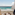 Tropical resort balcony overlooking turquoise ocean with chairs.