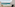 Tropical resort balcony overlooking turquoise ocean with chairs.