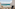 Tropical resort balcony overlooking turquoise ocean with chairs.