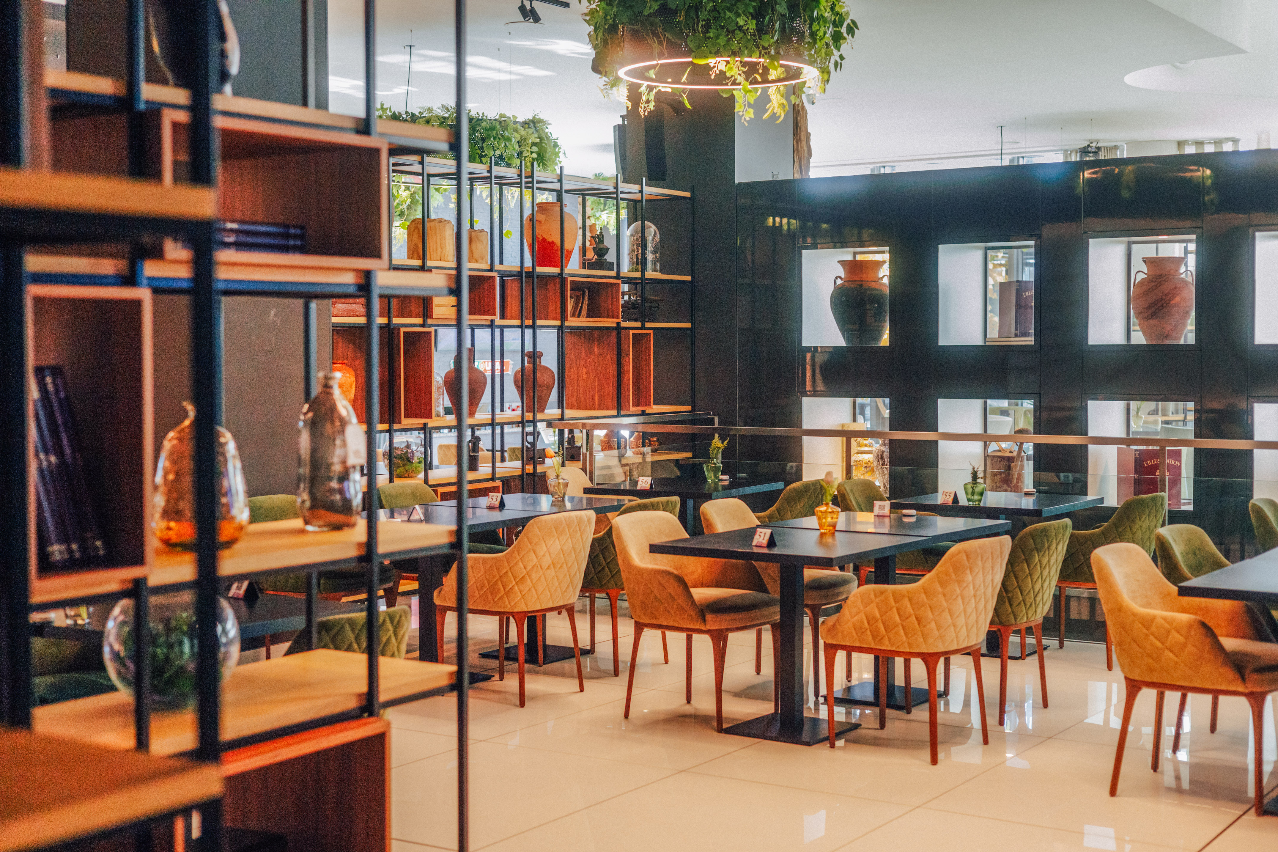 Modern restaurant interior with stylish chairs, tables, and decorated shelves.