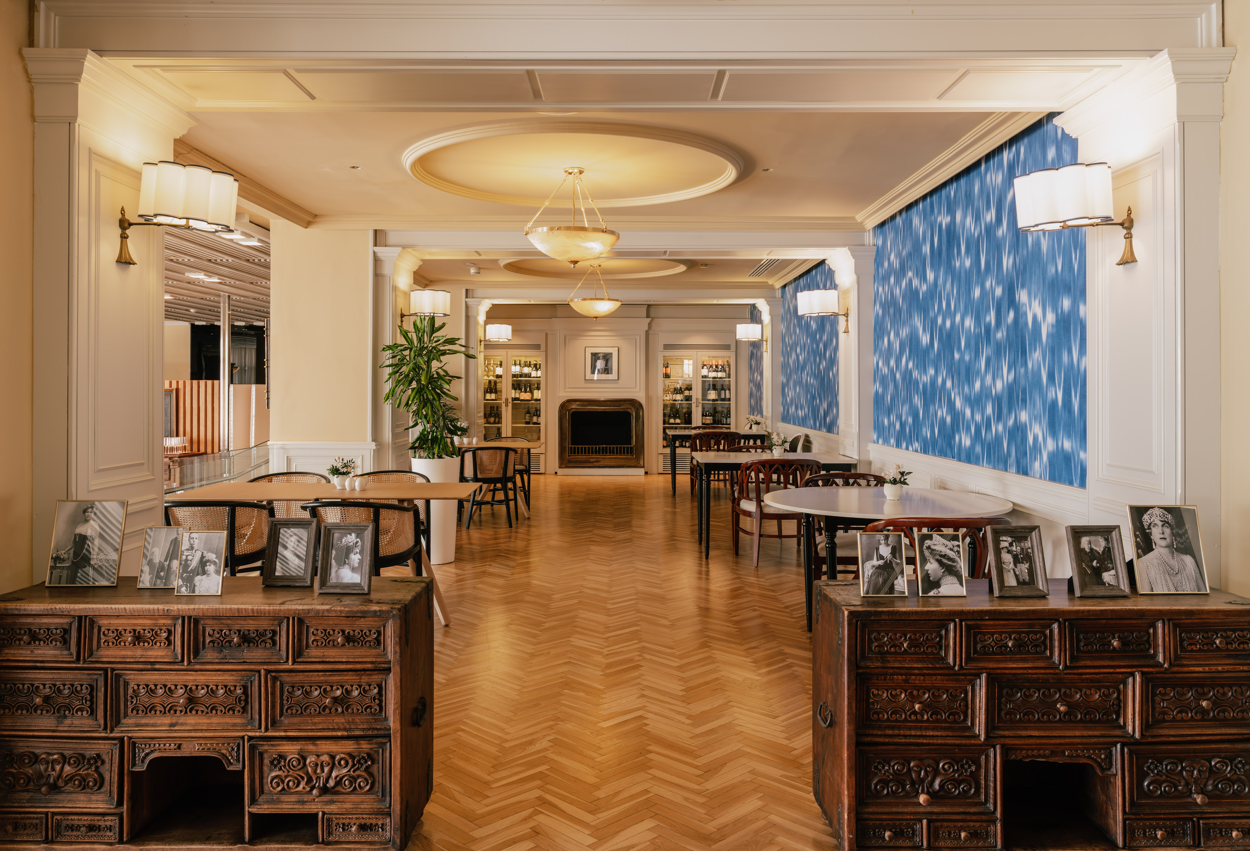 Elegant classic lounge with herringbone floor, blue wall, and vintage decor.