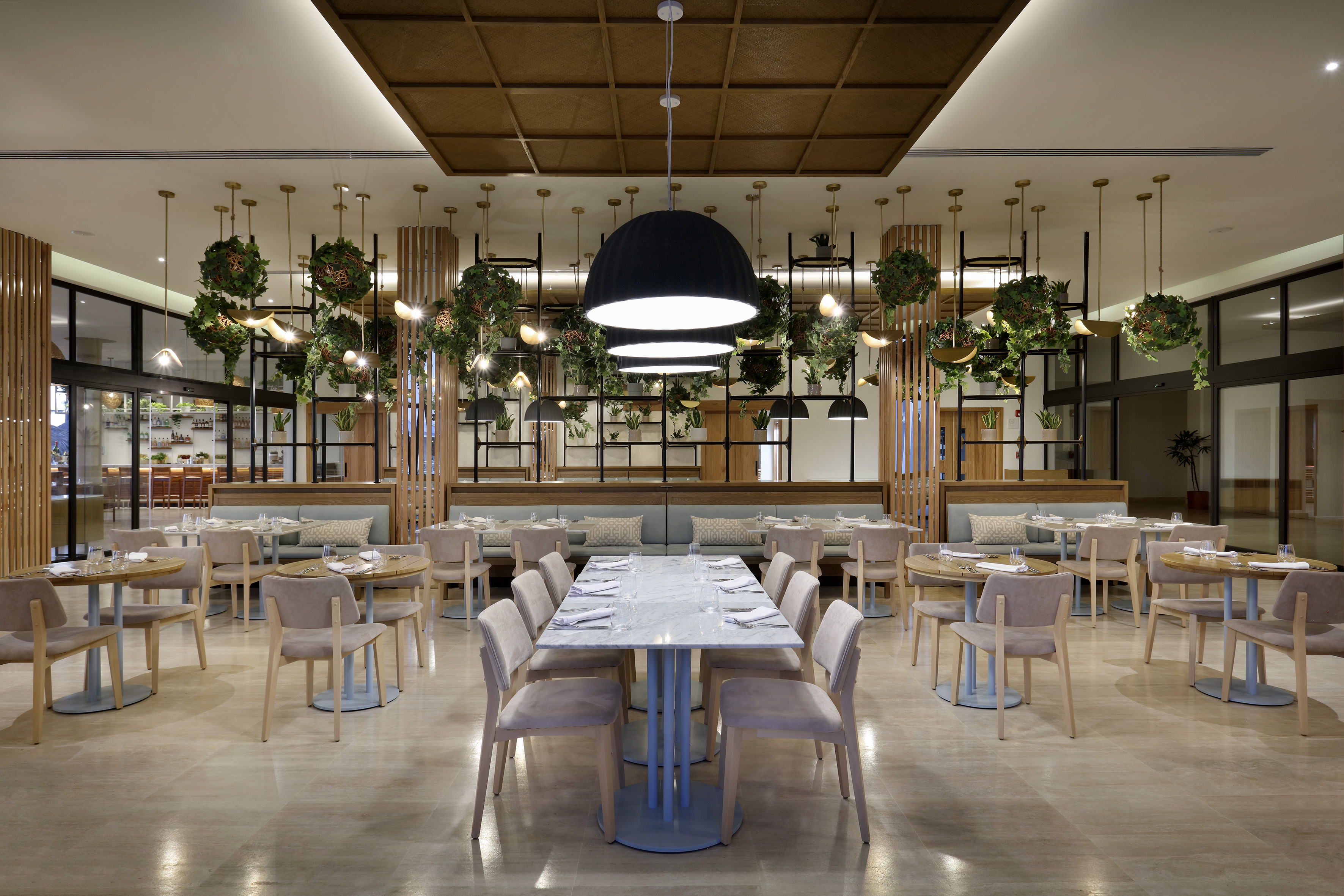 Modern restaurant with hanging plants, pendant lighting, and dining tables.