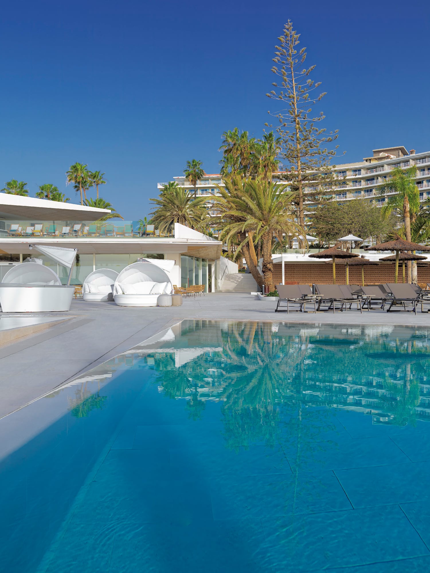 a swimming pool with lounge chairs and a building in the background