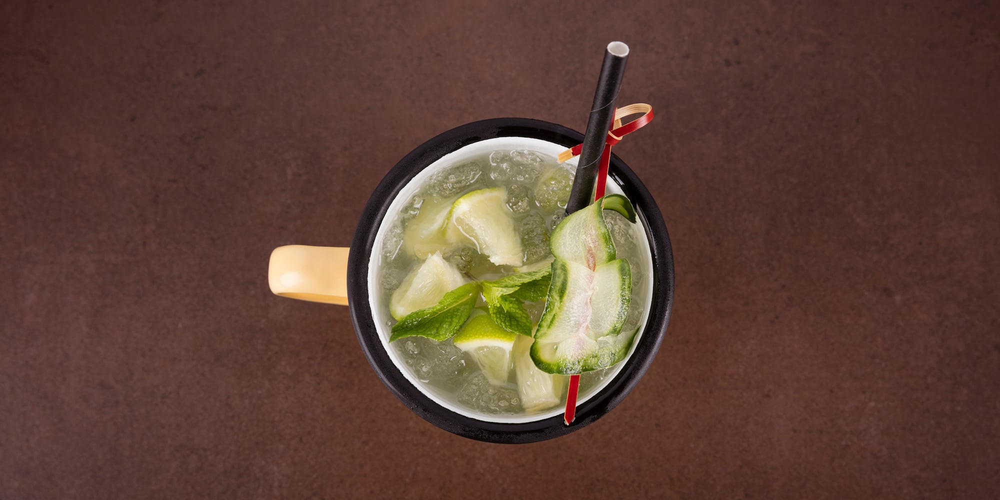 a cup of liquid with straws and cucumber slices
