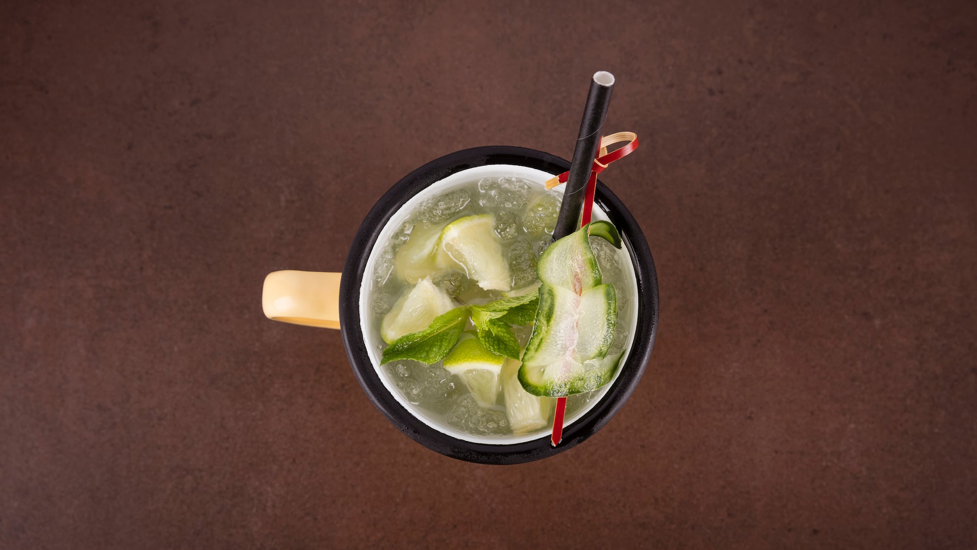 a cup of liquid with straws and cucumber slices