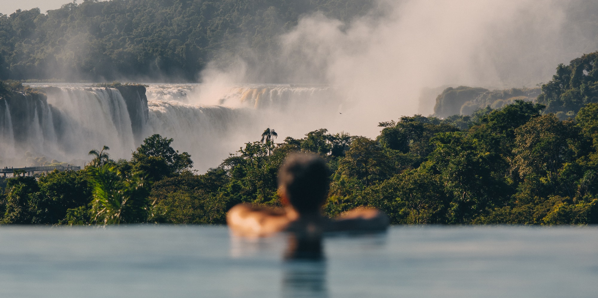 a person in a pool with a waterfall in the background