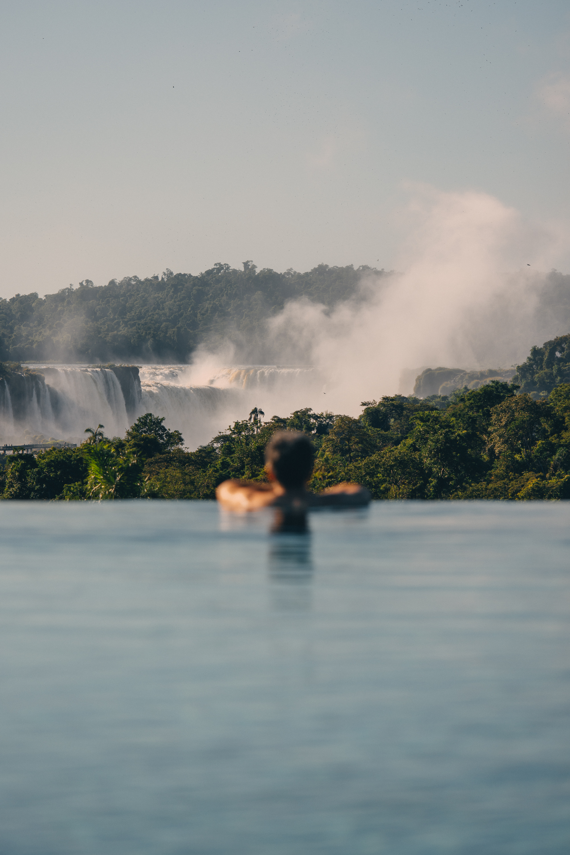 a person in a pool with a waterfall in the background