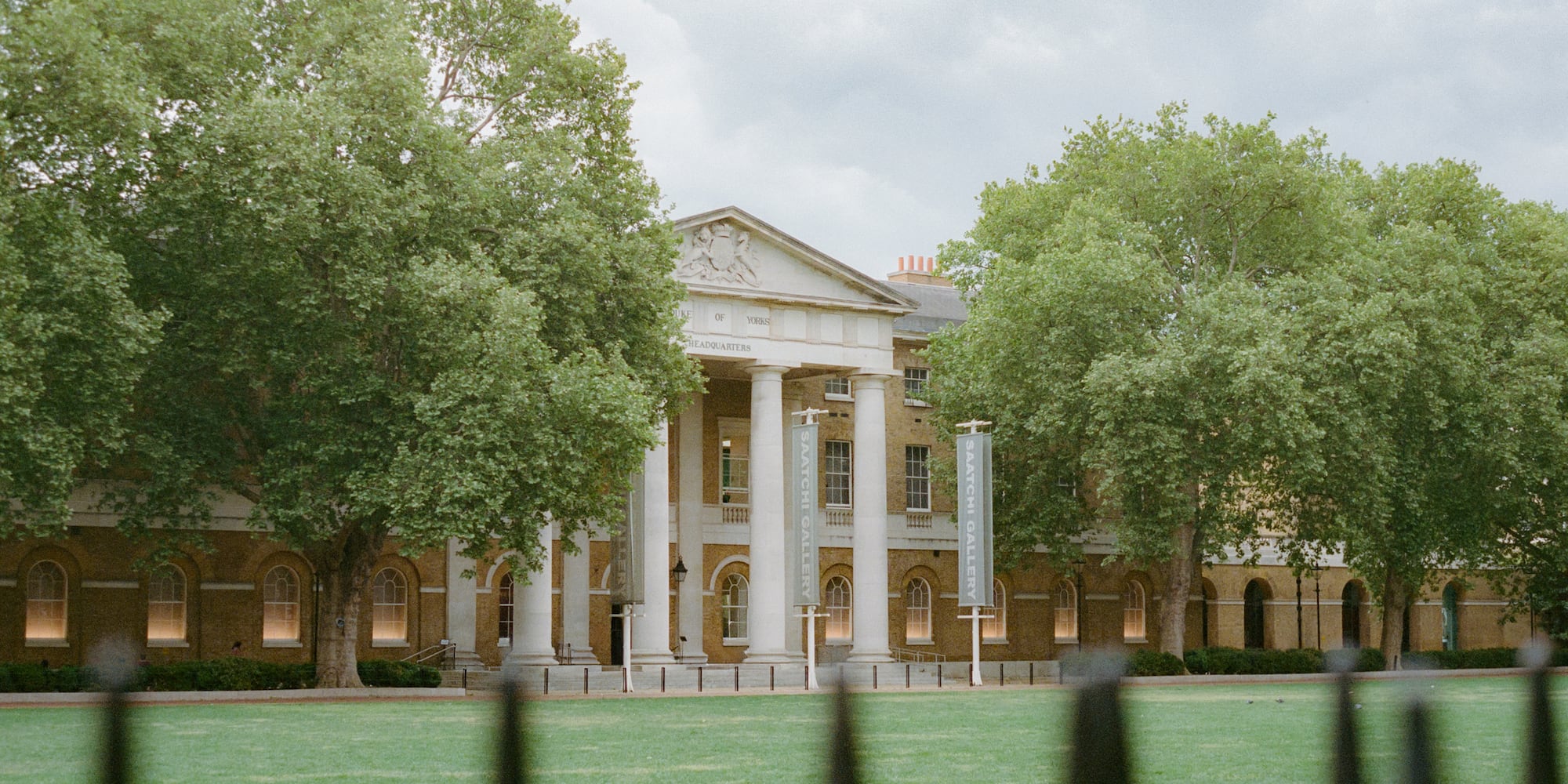 Saatchi Gallery, Londres: fachada neoclásica, columnas, árboles y césped verde.