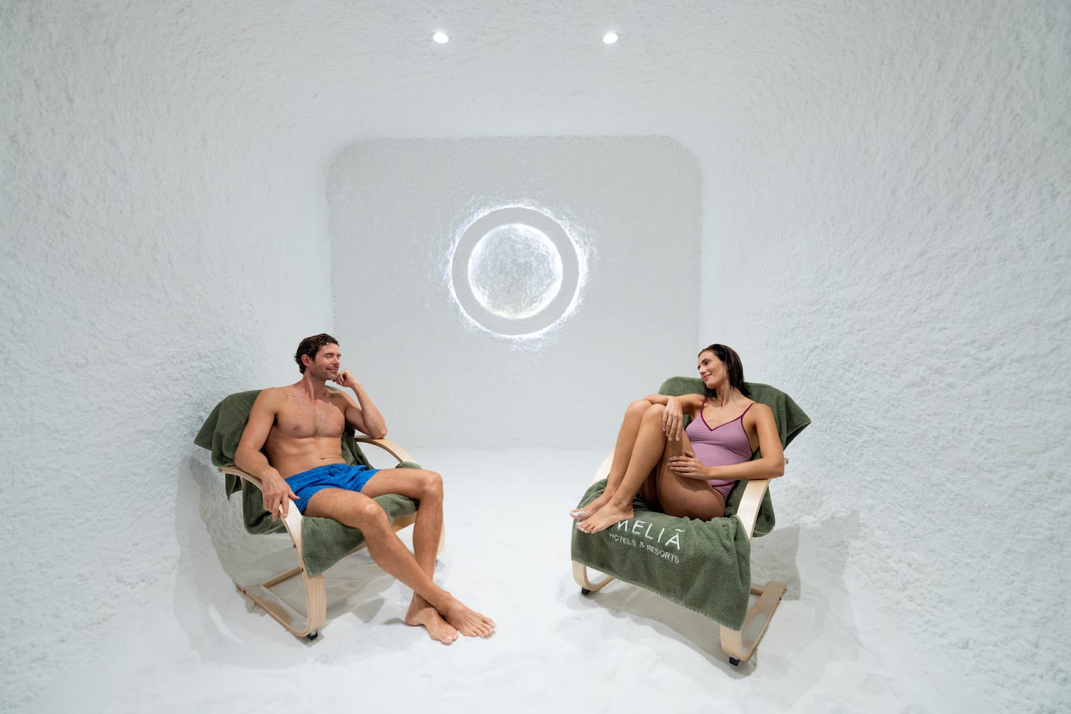 a man and woman sitting in chairs in a room with a round window