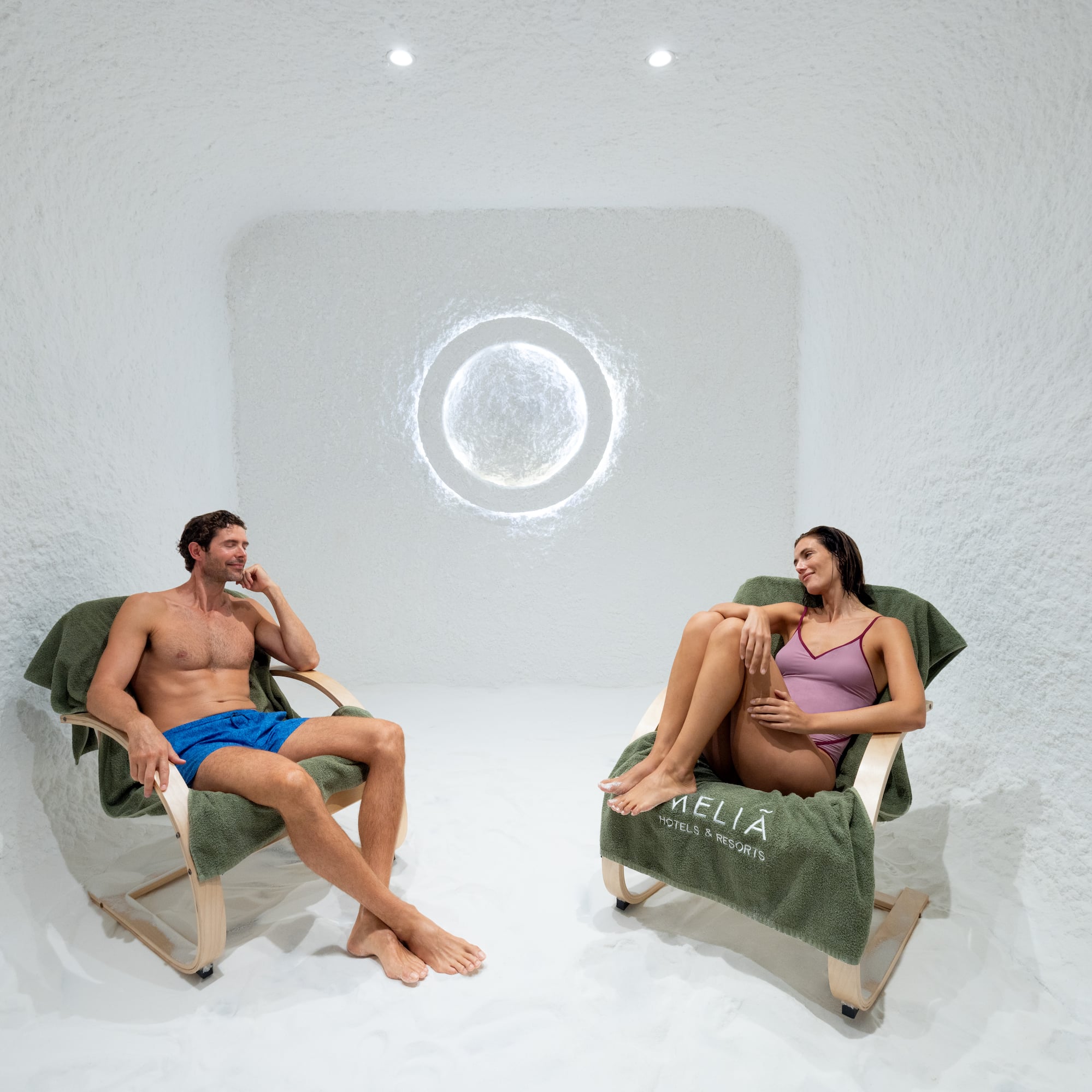 a man and woman sitting in chairs in a room with a round window