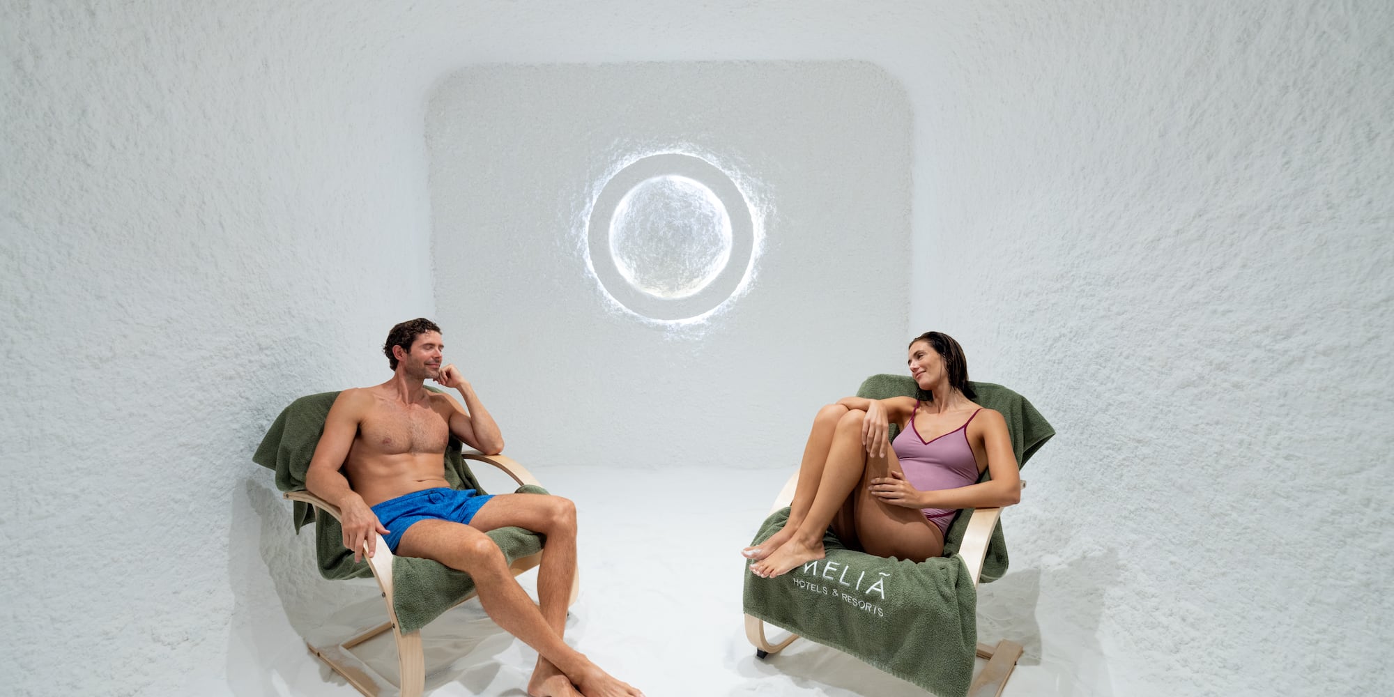 a man and woman sitting in chairs in a room with a round window