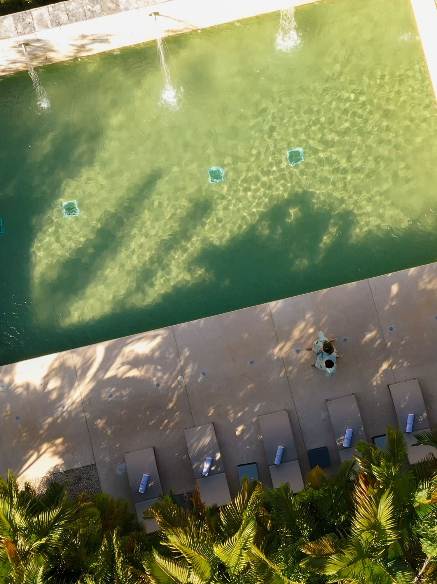 a pool with a fountain and chairs