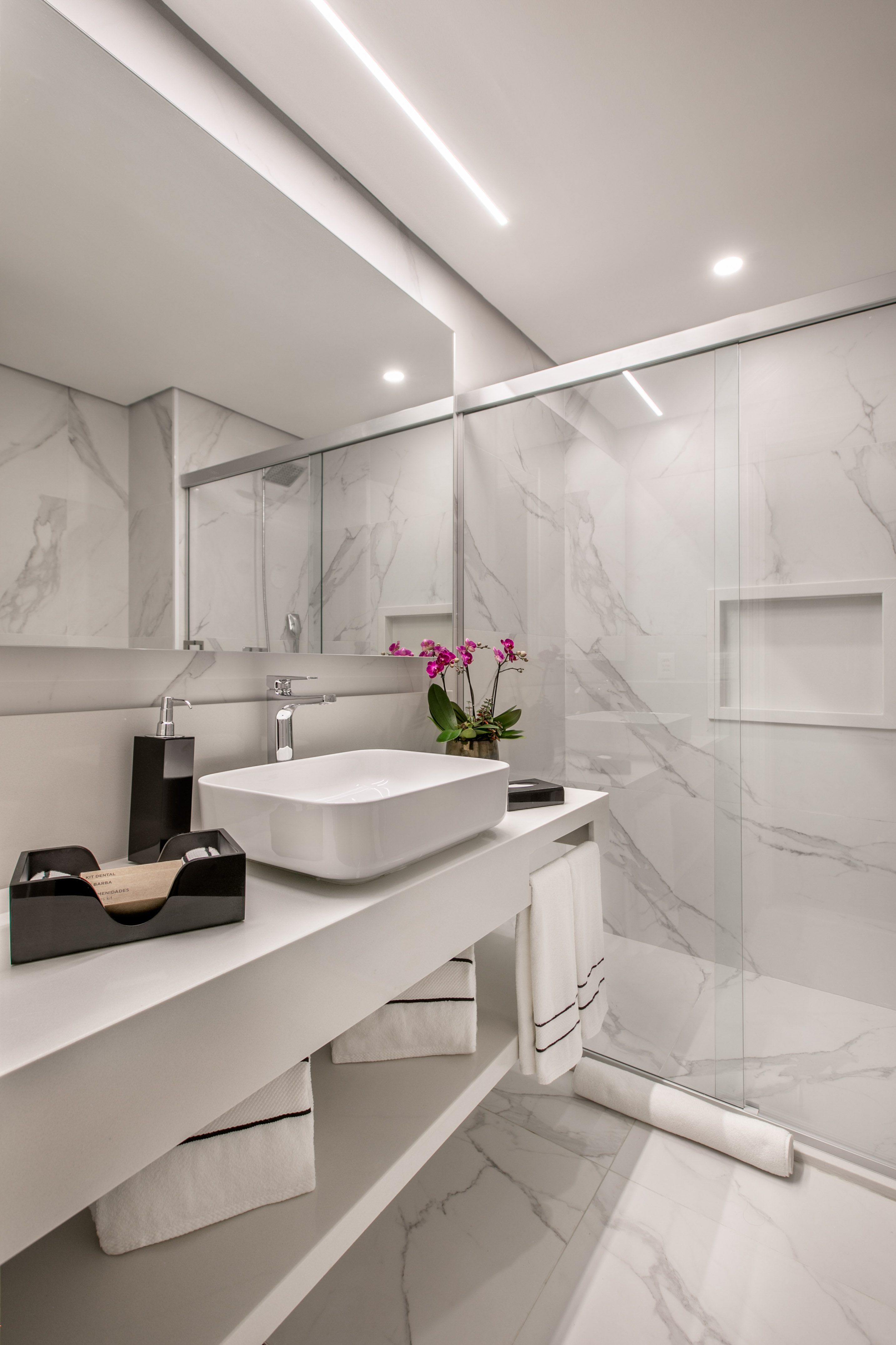 Modern white marble bathroom with vessel sink, sleek vanity, glass shower.