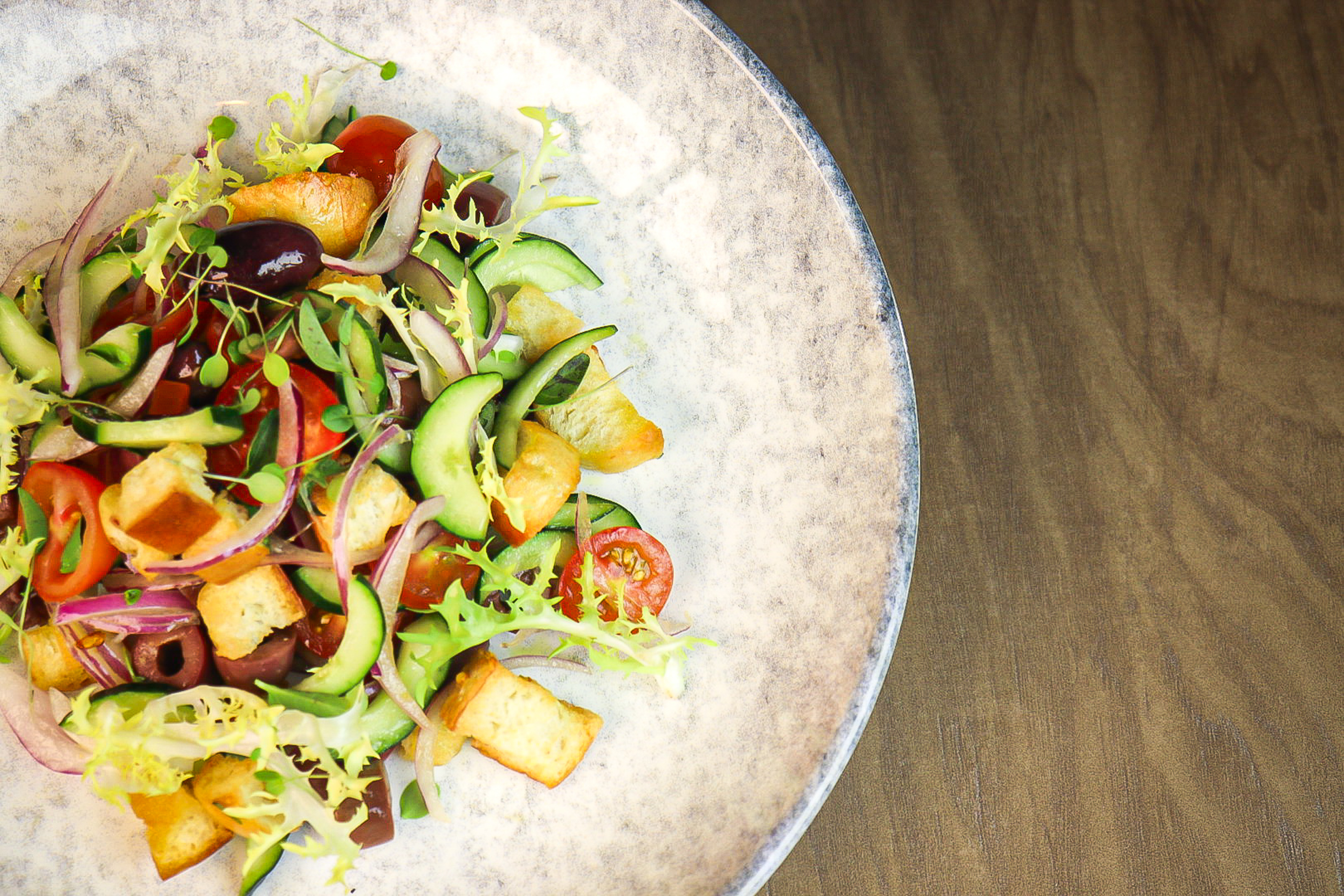 Fresh Mediterranean salad with tomatoes, cucumber, olives, red onion, croutons.