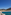 Marbella beach, Puente Romano red bridge, white hotel, and mountains under blue sky.