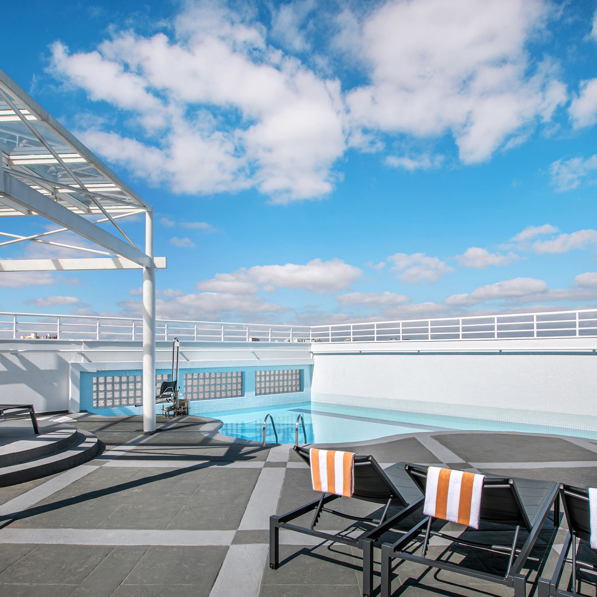 Modern rooftop pool, white pergola, lounge chairs, orange towels, blue sky. - São Paulo Nações Unidas Affiliated by Meliá, São Paulo
