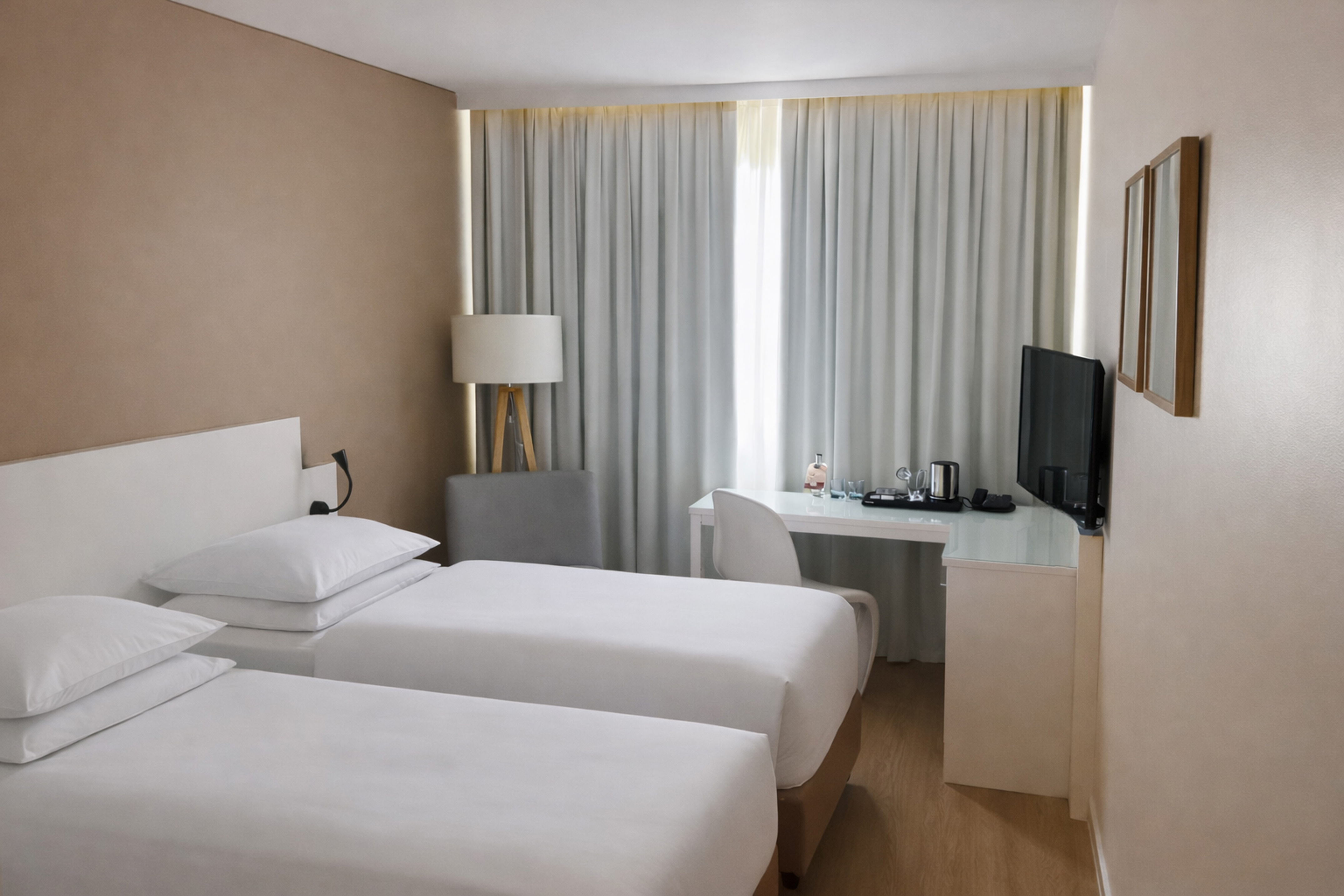 Modern hotel room with two single beds, desk, TV, and bright window.