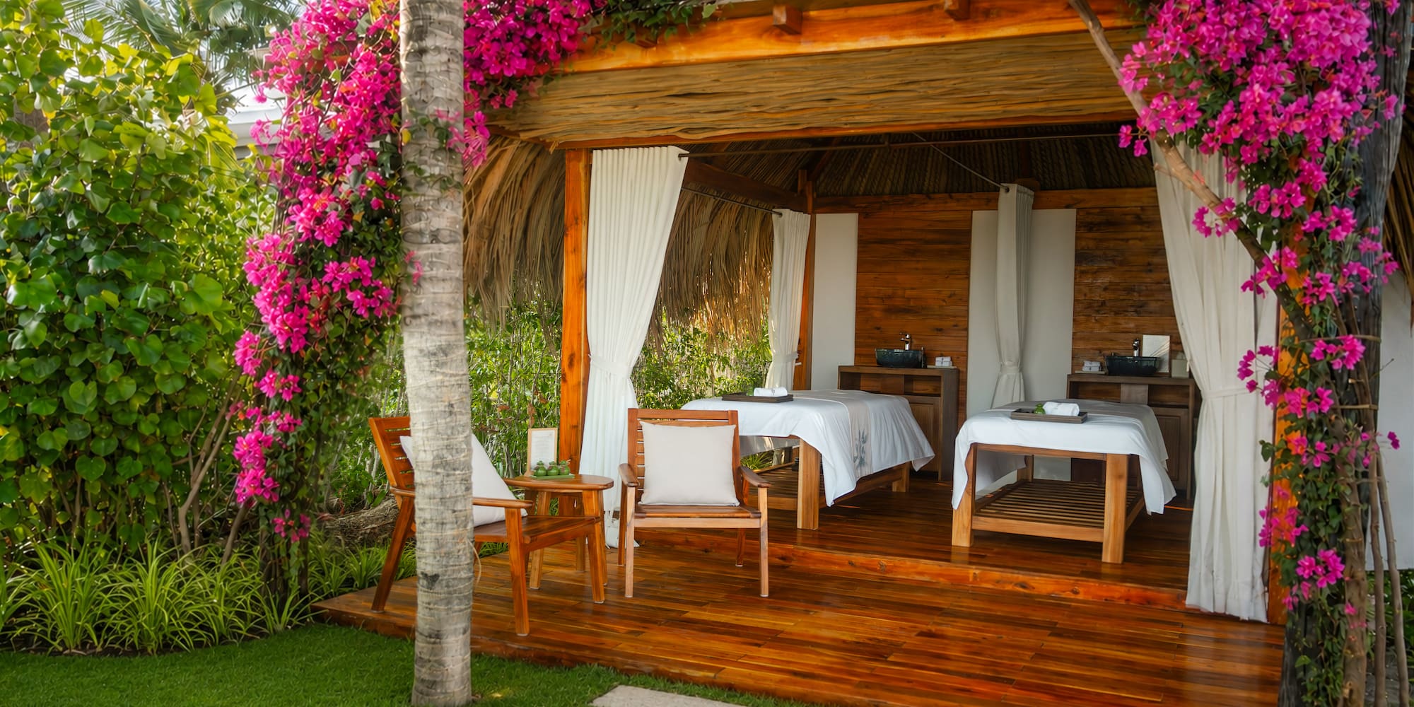Tropical outdoor spa cabana draped in pink bougainvillea, two massage beds.