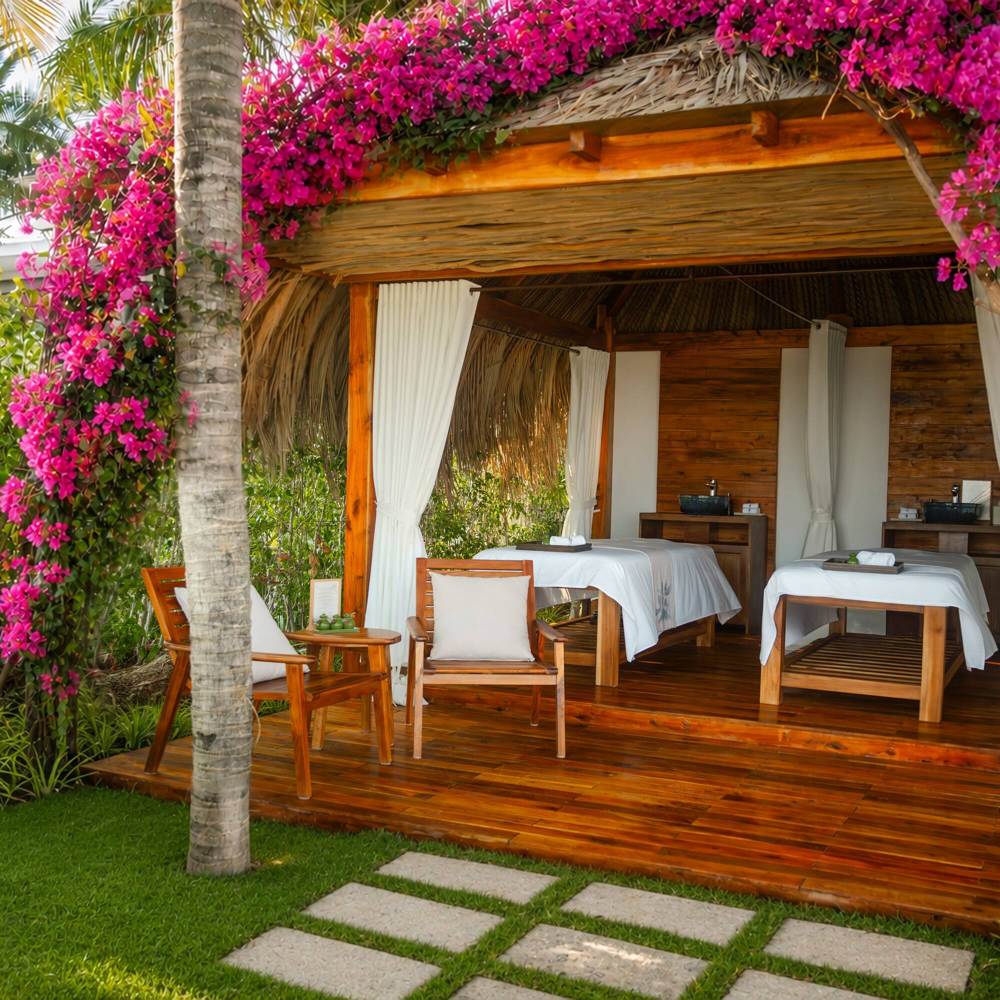 Tropical outdoor spa cabana draped in pink bougainvillea, two massage beds.