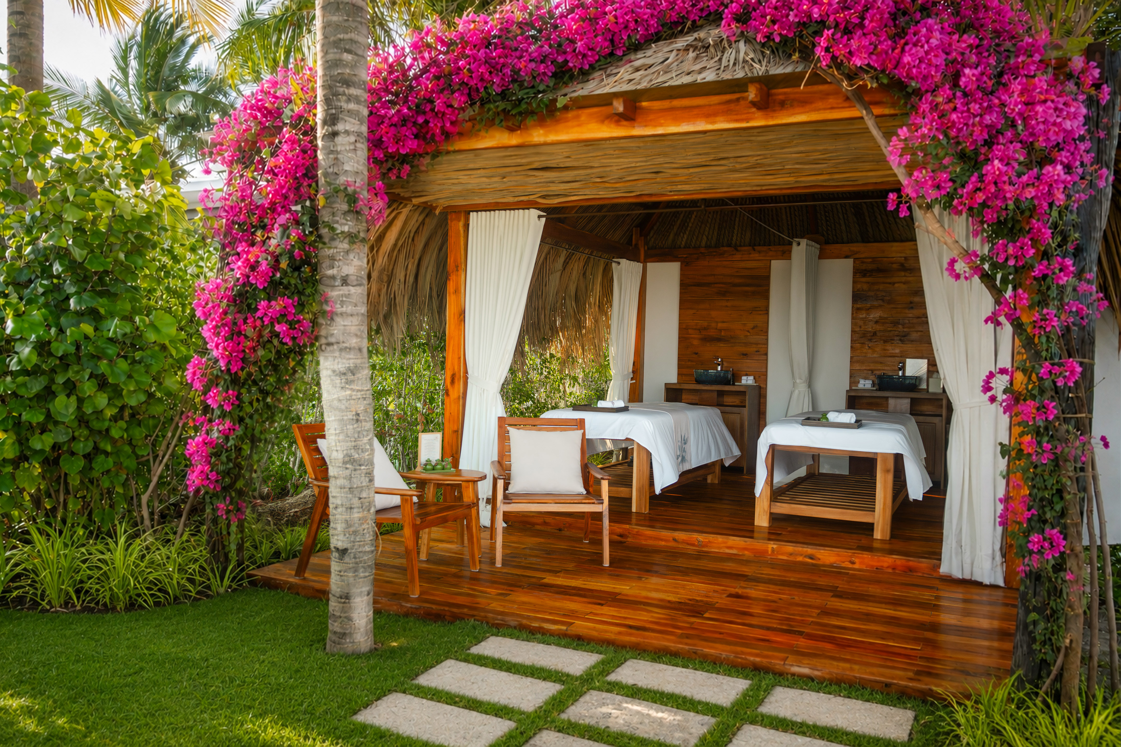Tropical outdoor spa cabana draped in pink bougainvillea, two massage beds.