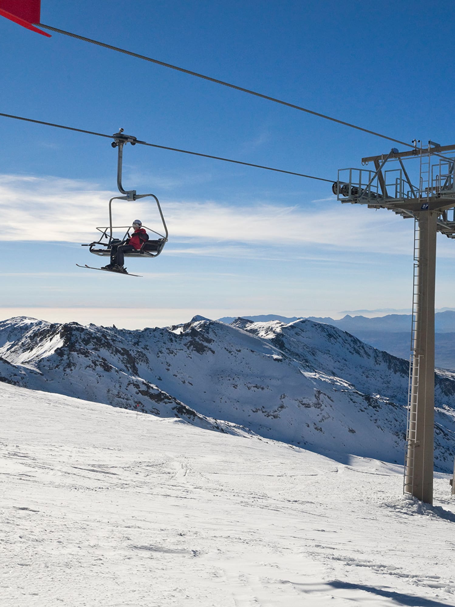 a person on a ski lift above a snowy mountain