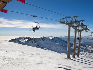a person on a ski lift above a snowy mountain