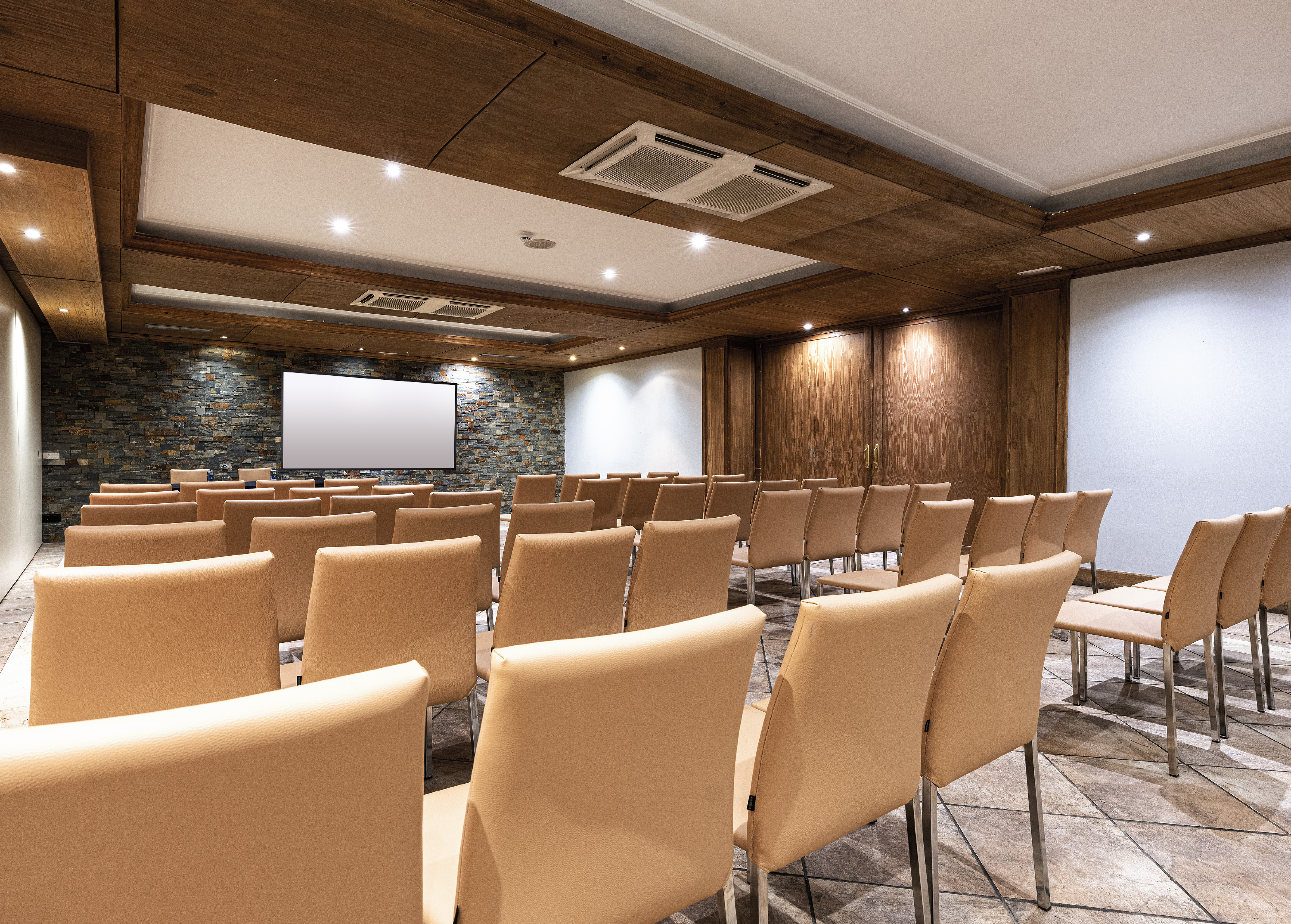 Empty conference room with tan chairs, projection screen, and wood ceiling.