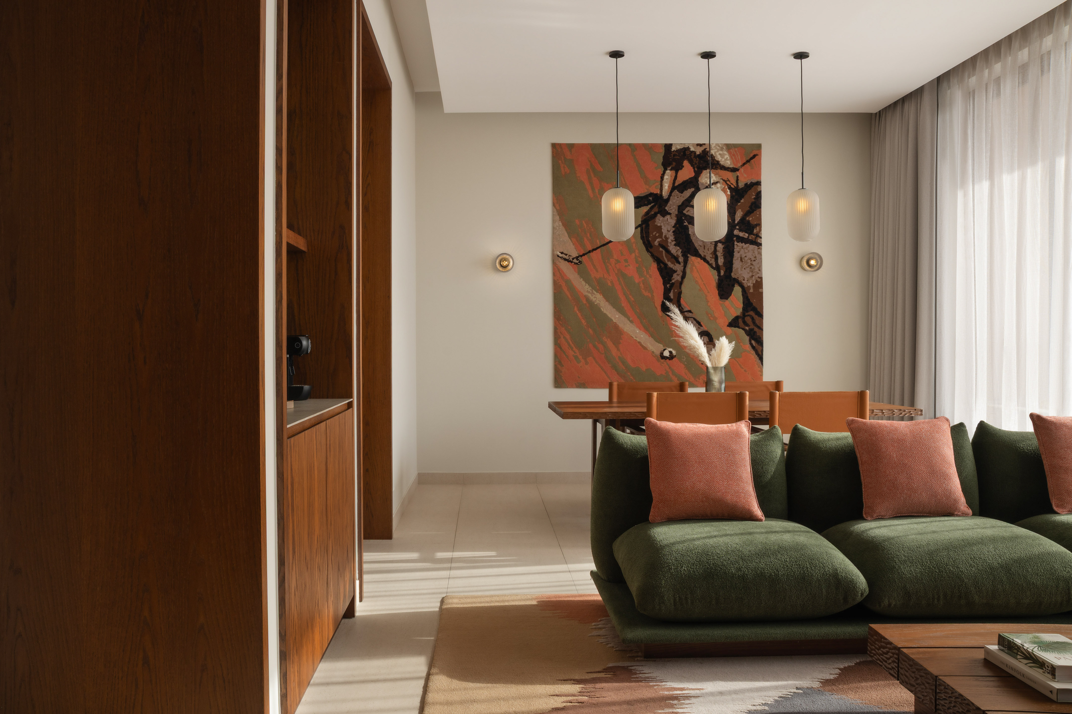 Modern living dining area: green sofa, wood coffee table, equestrian art.