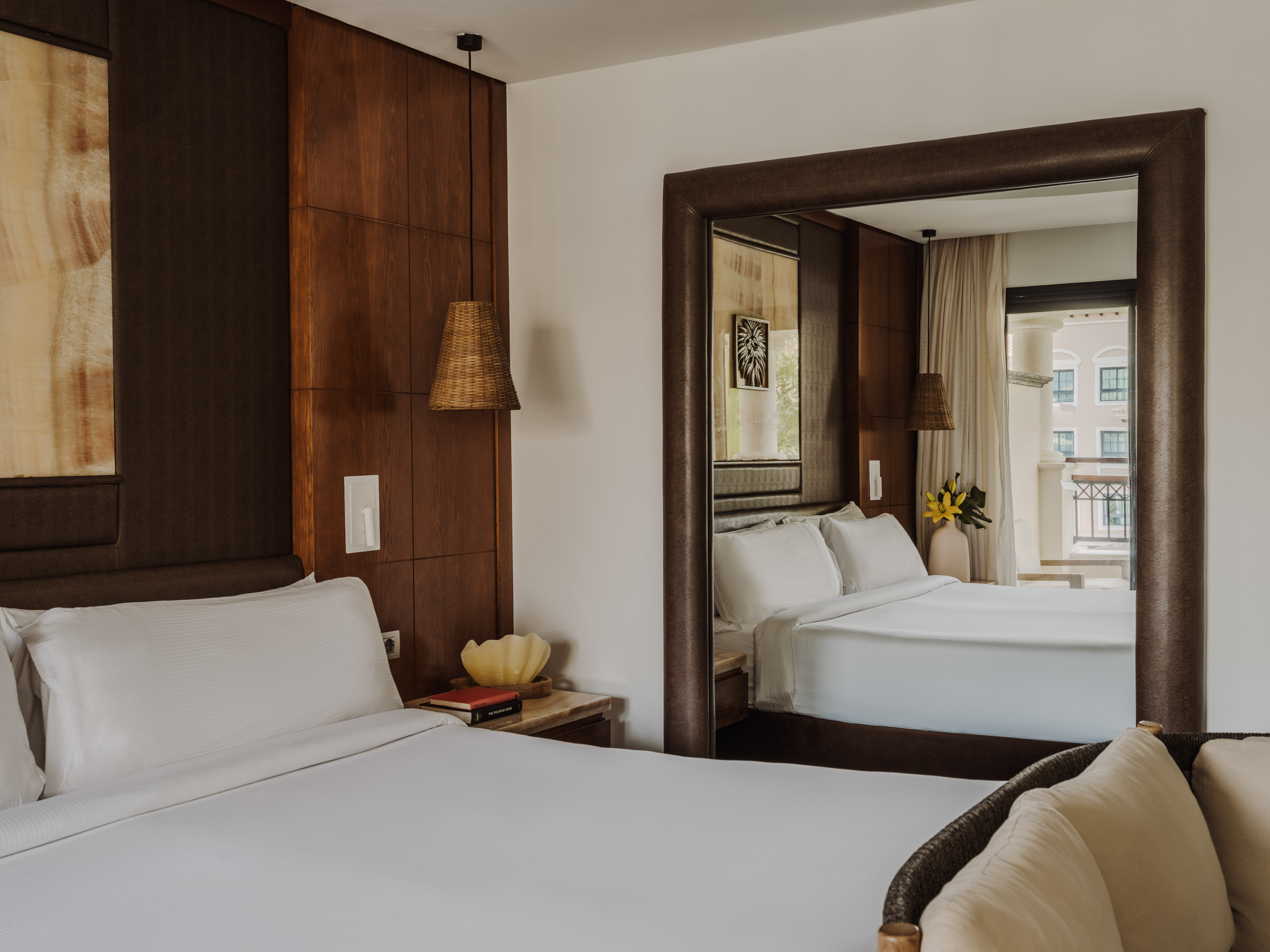 Modern hotel bedroom, king bed, wood accent wall, and large mirror.