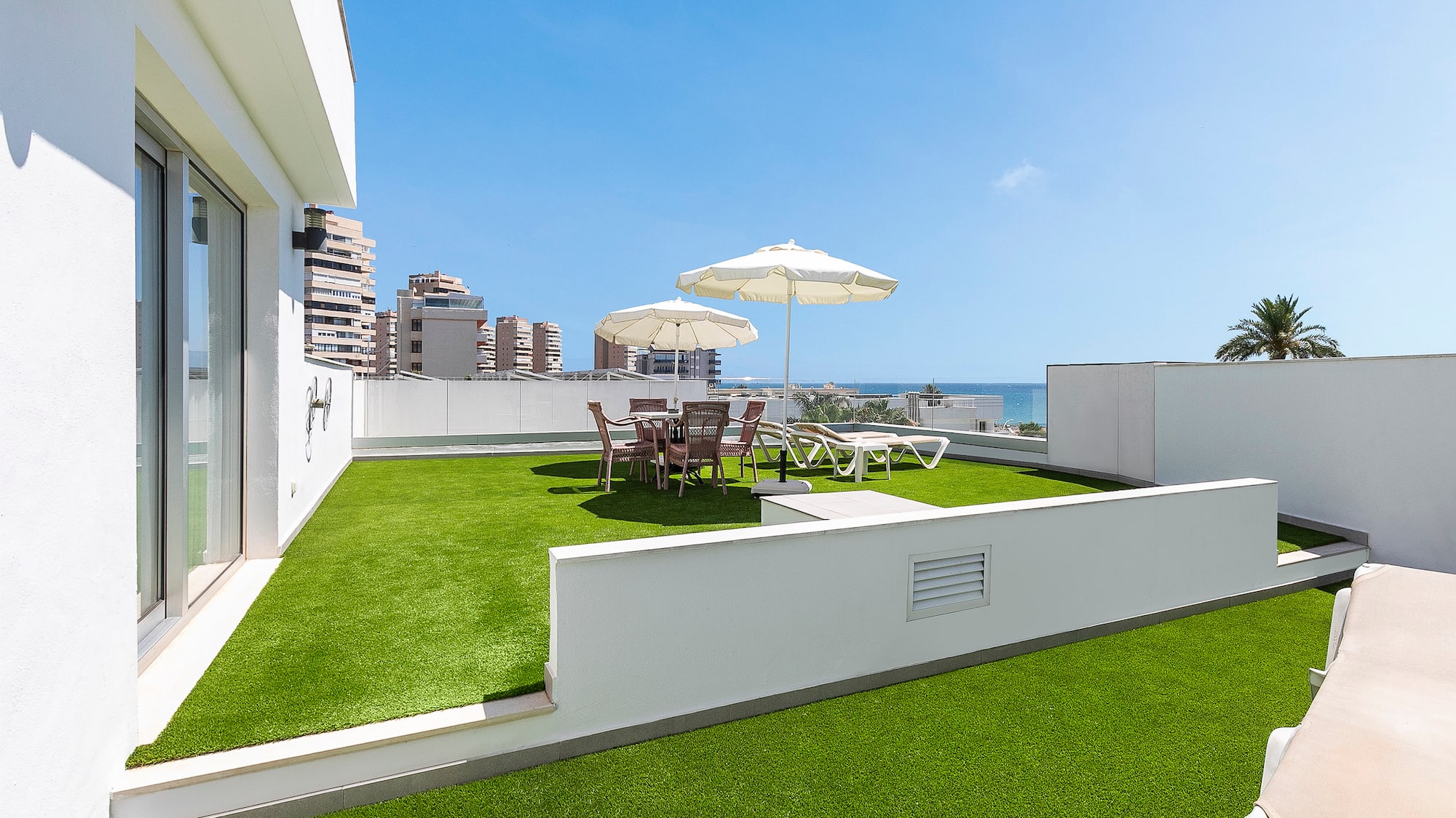 a patio with umbrellas and chairs on a green lawn